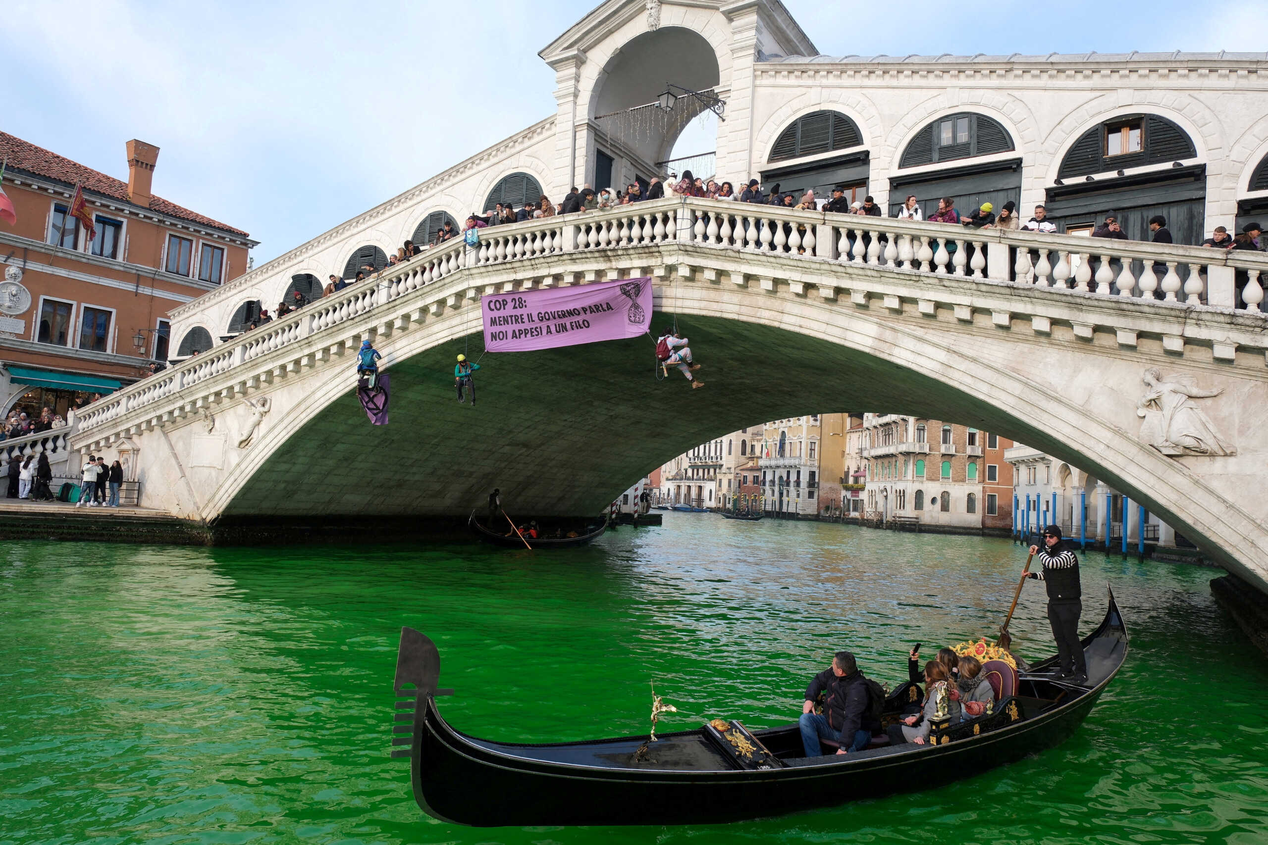 People ride in boats as waters of Grand Canal turned green after a protest by 'Extinction Rebellion' climate activists in Venice, Italy, December 9, 2023. REUTERS