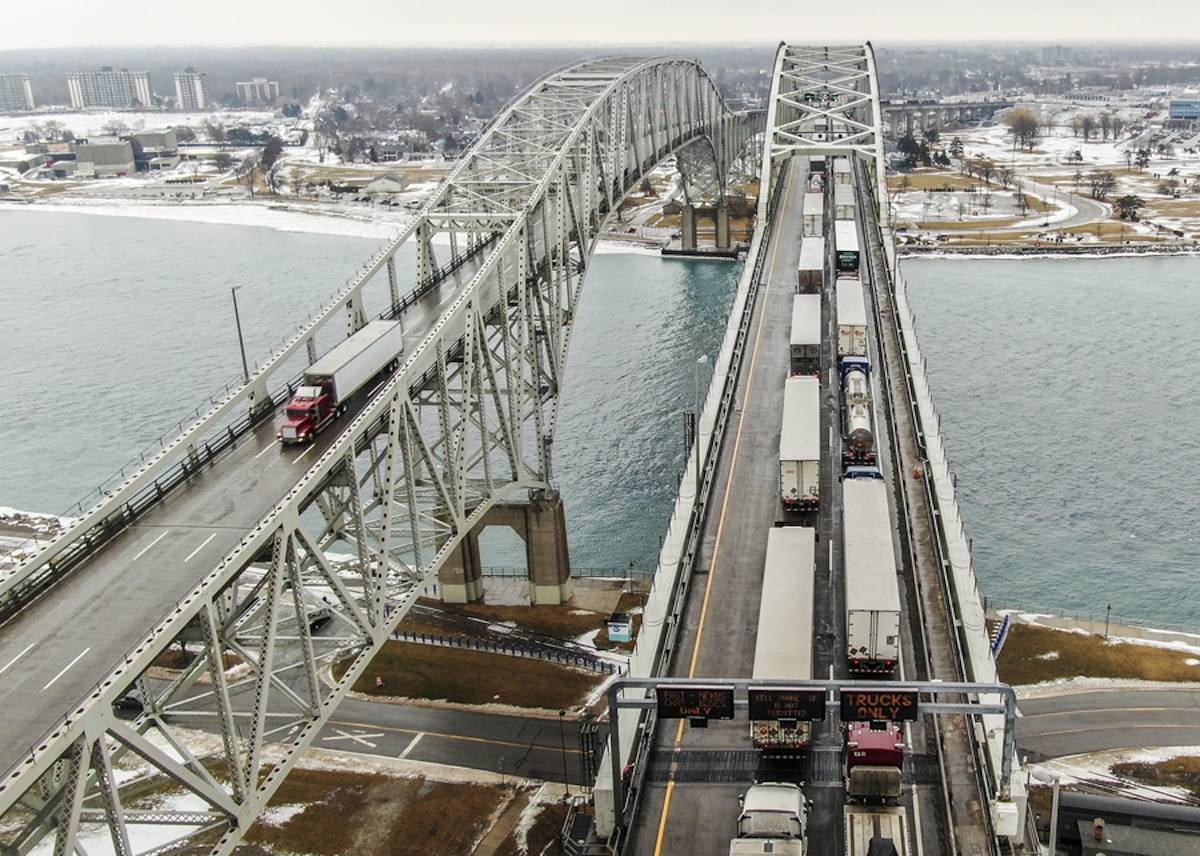 epa09747780 An aerial photo made with a drone shows trucks (R) going into Canada backed up on the Blue Water Bridge over the St. Clair River that links the US and Canada between Port Edward, Ontario, Canada and Port Huron, Michigan, USA, 11 February 2022. Canadian truckers protesting the vaccine mandate have shut down the Ambassador Bridge at Detroit, Michigan, USA, a vital link where 25 percent of goods between the two countries passes, forcing vehicles to re-route over the Blue Water Bridge.  EPA