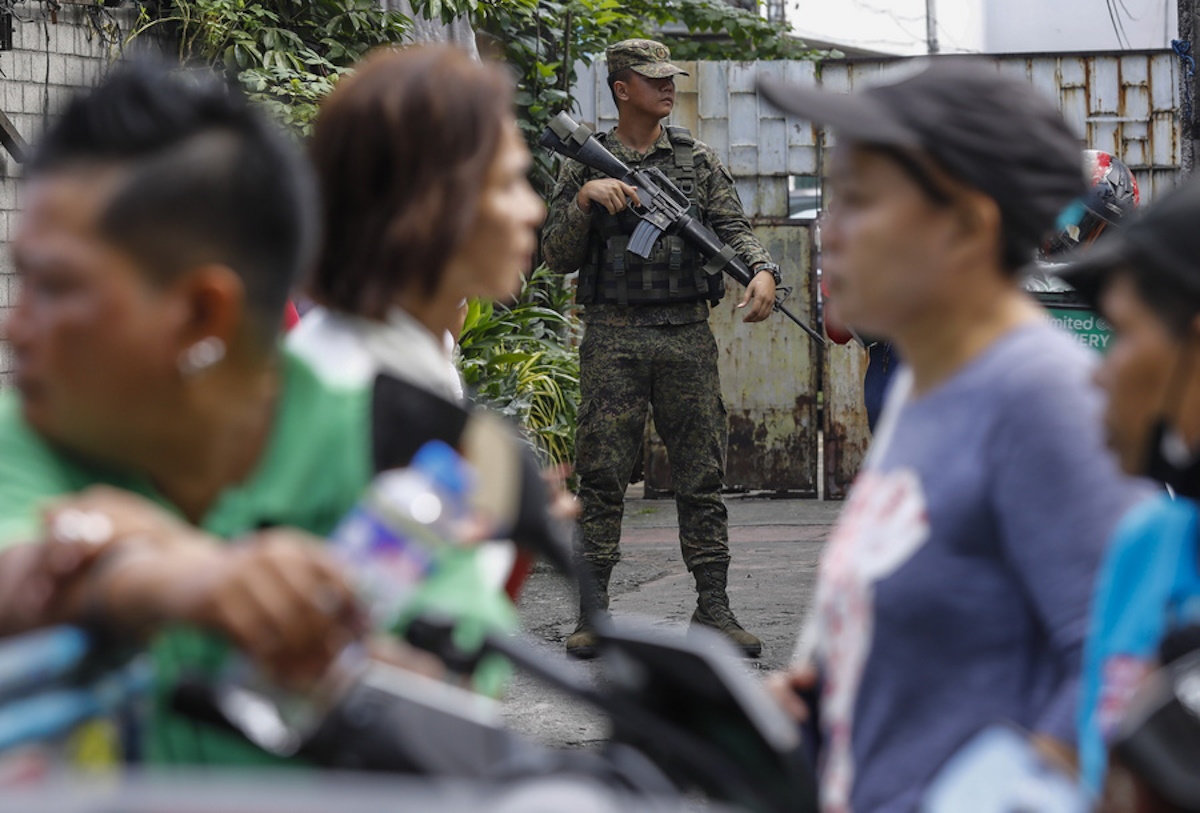 epa10948507 A Philippine Army soldier keeps watch across the road from the Pasong Tamo Elementary School, a pilot venue for the automated system of the Barangay and Sangguniang Kabataan (village and youth council) elections in Quezon City, Metro Manila, Philippines 30 October 2023. Registered voters nationwide headed for precincts to elect candidates who will take positions as local village leaders and youth council representatives in some 42,000 villages all over the country.  EPA