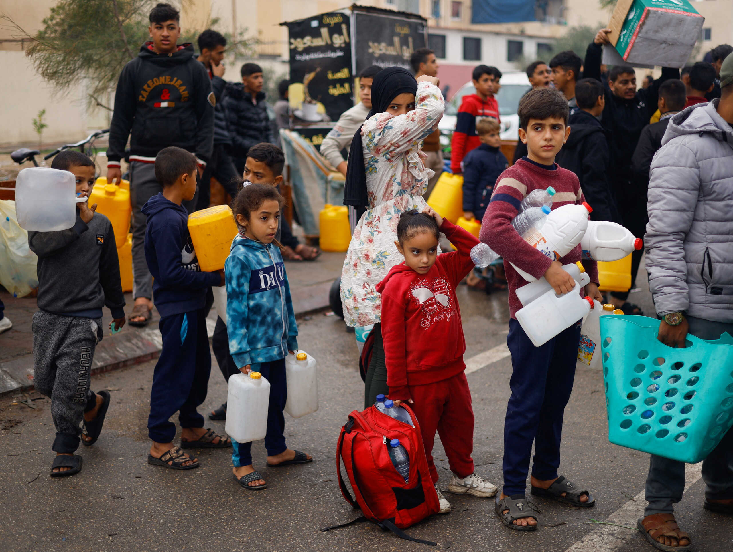 Palestinian children queue to collect water amid water shortages during the ongoing conflict between Israel and Palestinian Islamist group Hamas, in Rafah in the southern Gaza Strip, December 5, 2023. REUTERS