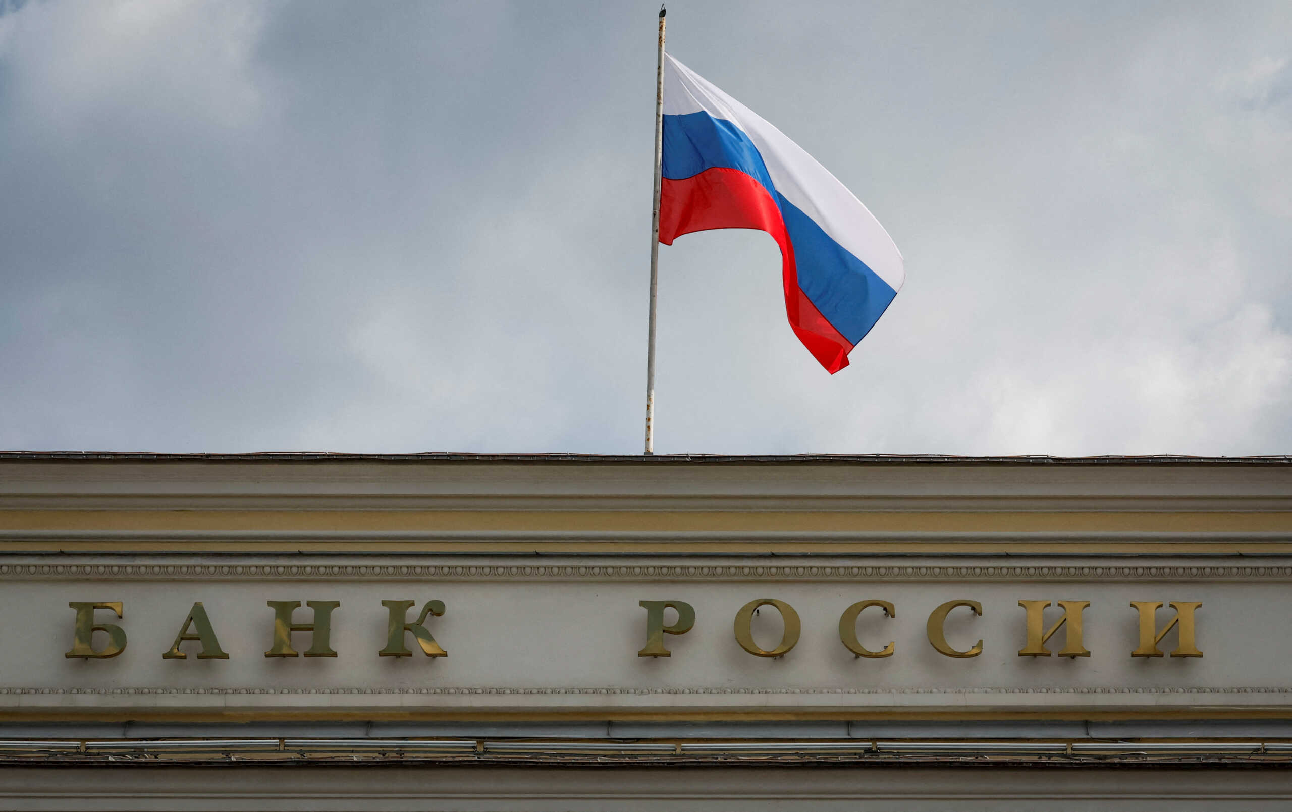 FILE PHOTO: A Russian state flag flies over the Central Bank headquarters in Moscow, Russia, August 15, 2023. A sign reads: "Bank of Russia". REUTERS