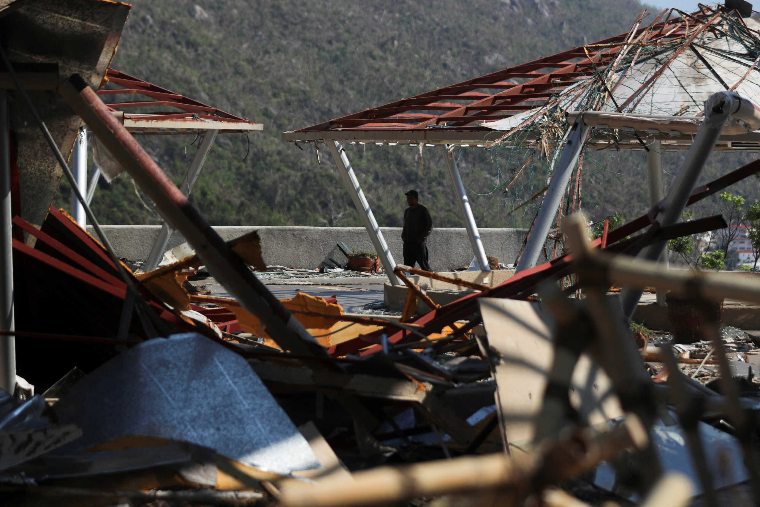 A man walks among debris a month after Hurricane Otis hit Acapulco, Mexico November 25, 2023. REUTERS