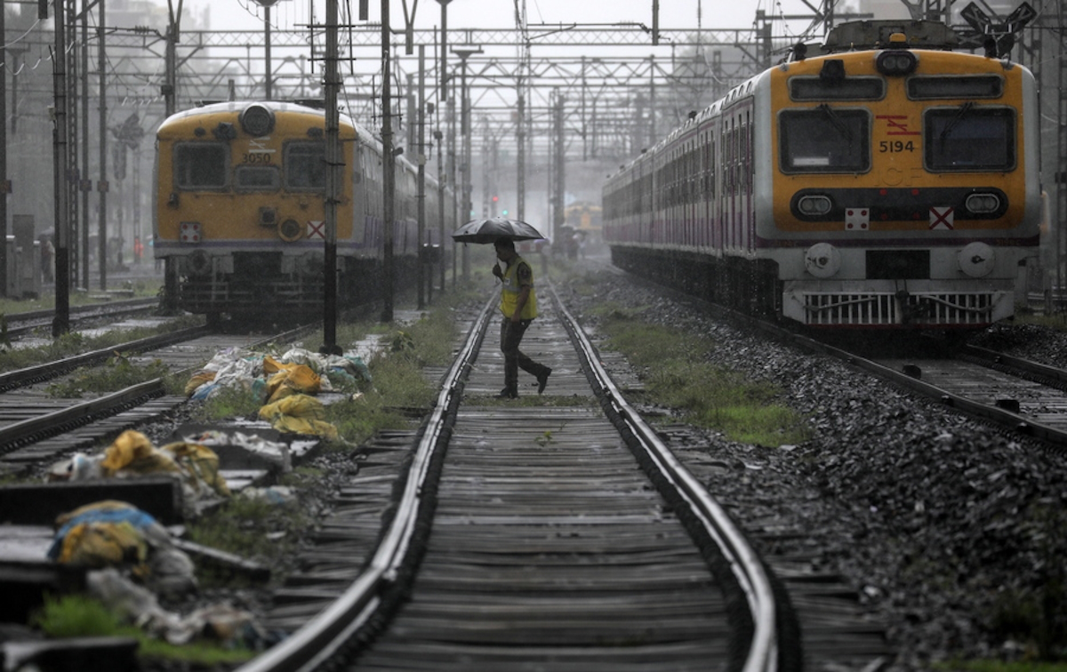 epa06860034 An Indian policeman crosses the track infront of halted local trains at the site of a pedestrian bridge that collapsed at Andheri railway station in Mumbai, India, 03 July 2018. According to reports, a pedestrian bridge caved in at Andheri station in the morning during heavy rains.  EPA
