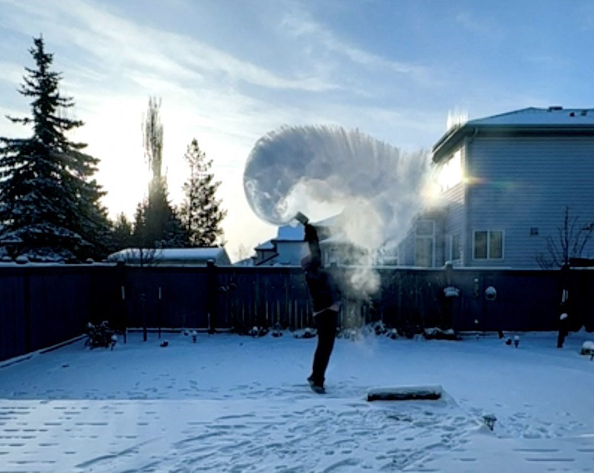 A view shows a man throwing hot water amidst extreme temperatures, in Edmonton, Alberta, Canada,  January 11, 2024. in this screen grab taken from a video. Joe Chowaniec Images