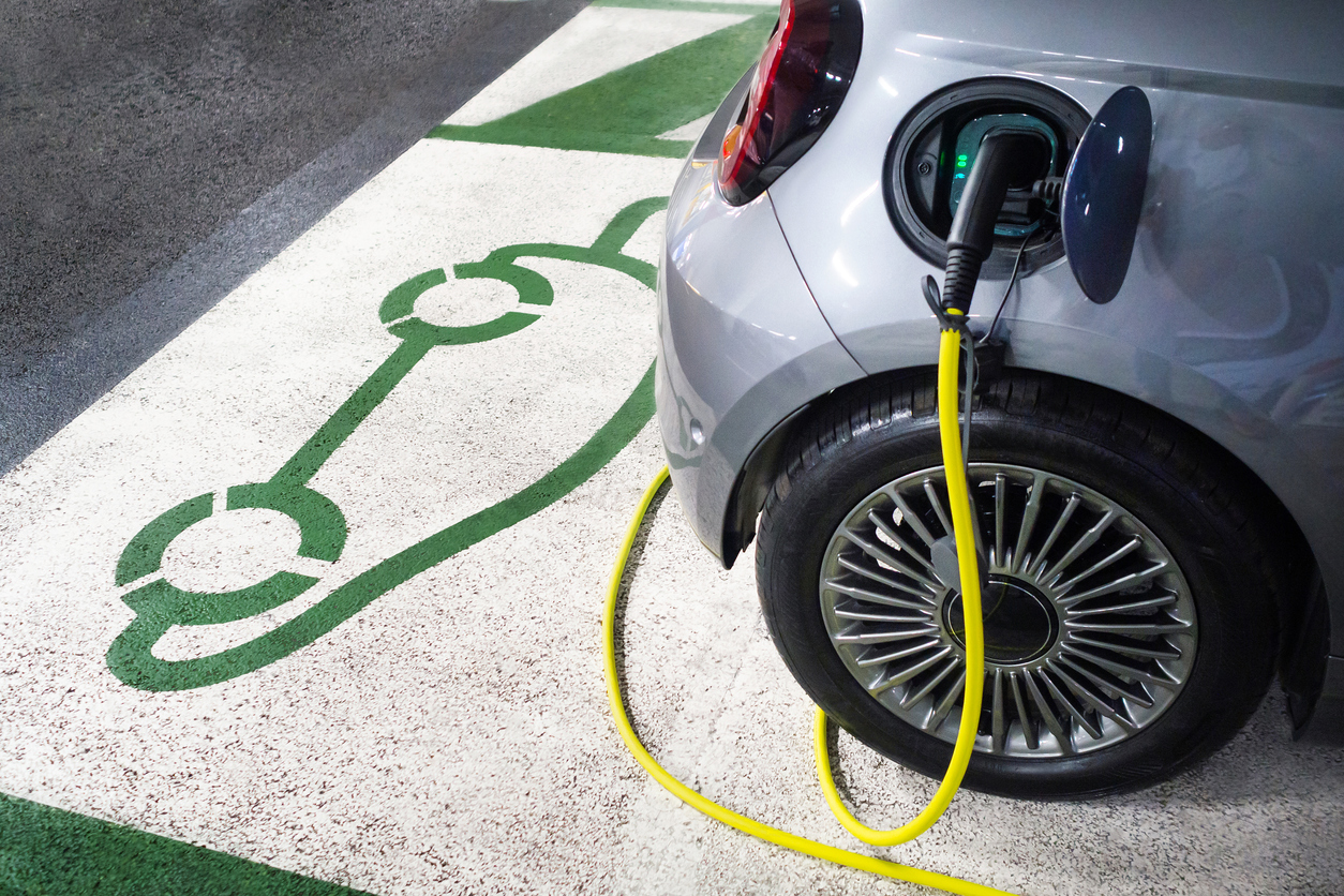 Electric car charging at parking charging station.
