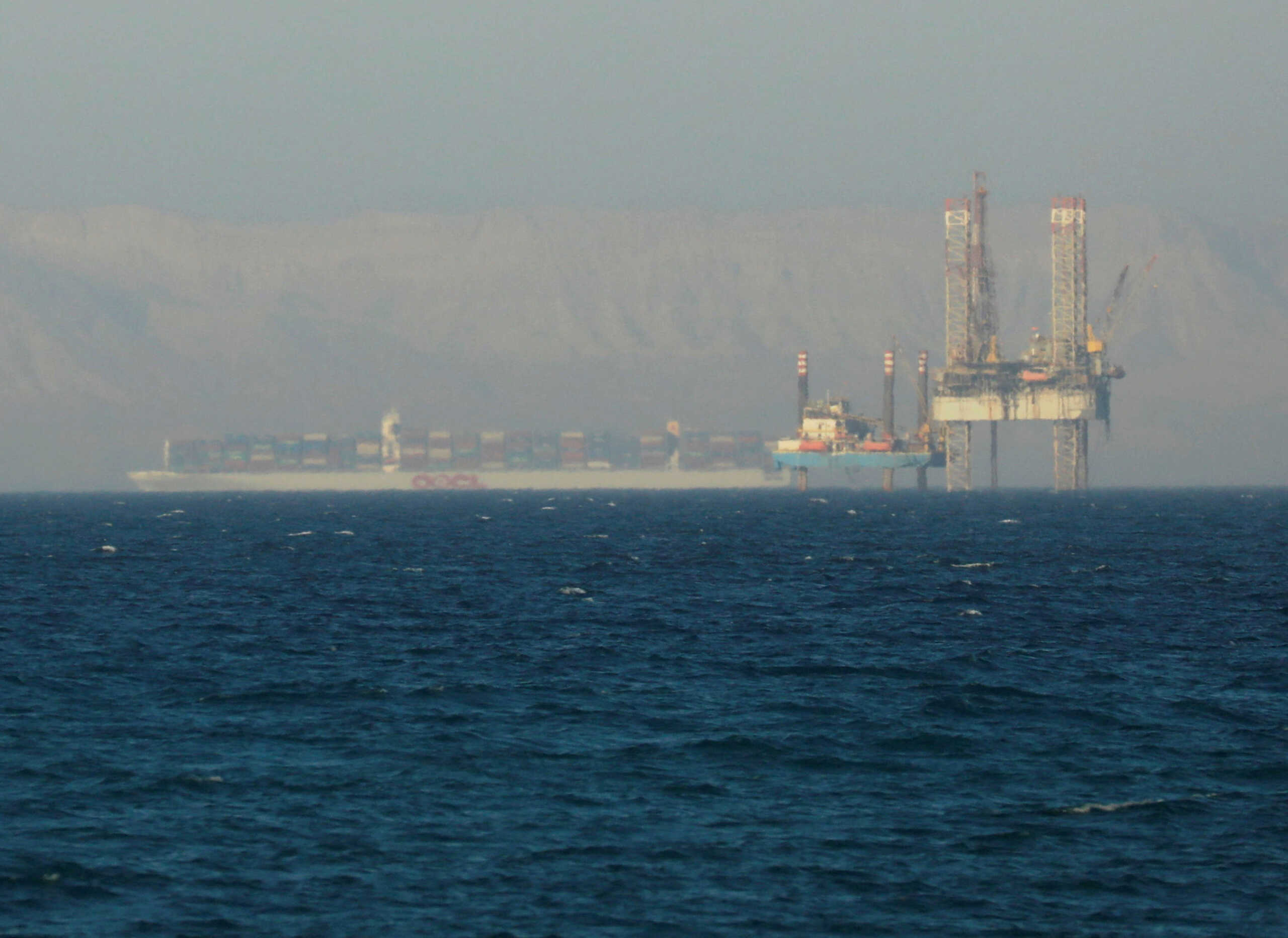 FILE PHOTO: FILE PHOTO: A container ship crosses an oil platform at the Gulf of Suez towards the Red Sea before entering the Suez Canal, outside of Cairo, Egypt September 1, 2020. REUTERS