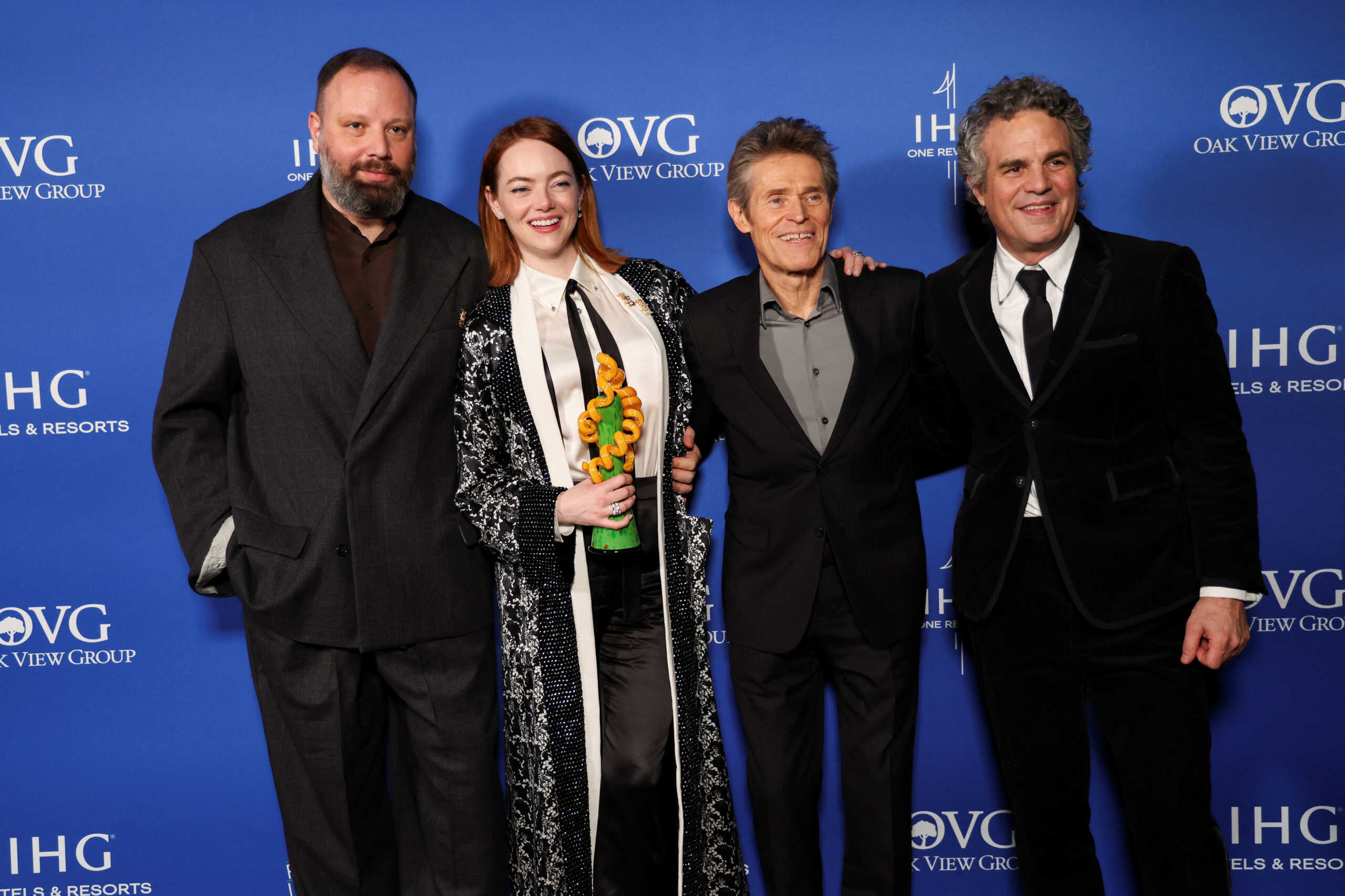 Yorgos Lanthimos, Mark Ruffalo and Willem Dafoe stand next to Emma Stone, winner of the Desert Palm Achievement Award - Actress for "Poor Things" as she poses with her award at the 35th Annual Palm Springs International Film Festival Film Awards in Palm Springs, California, U.S., January 4, 2024. REUTERS