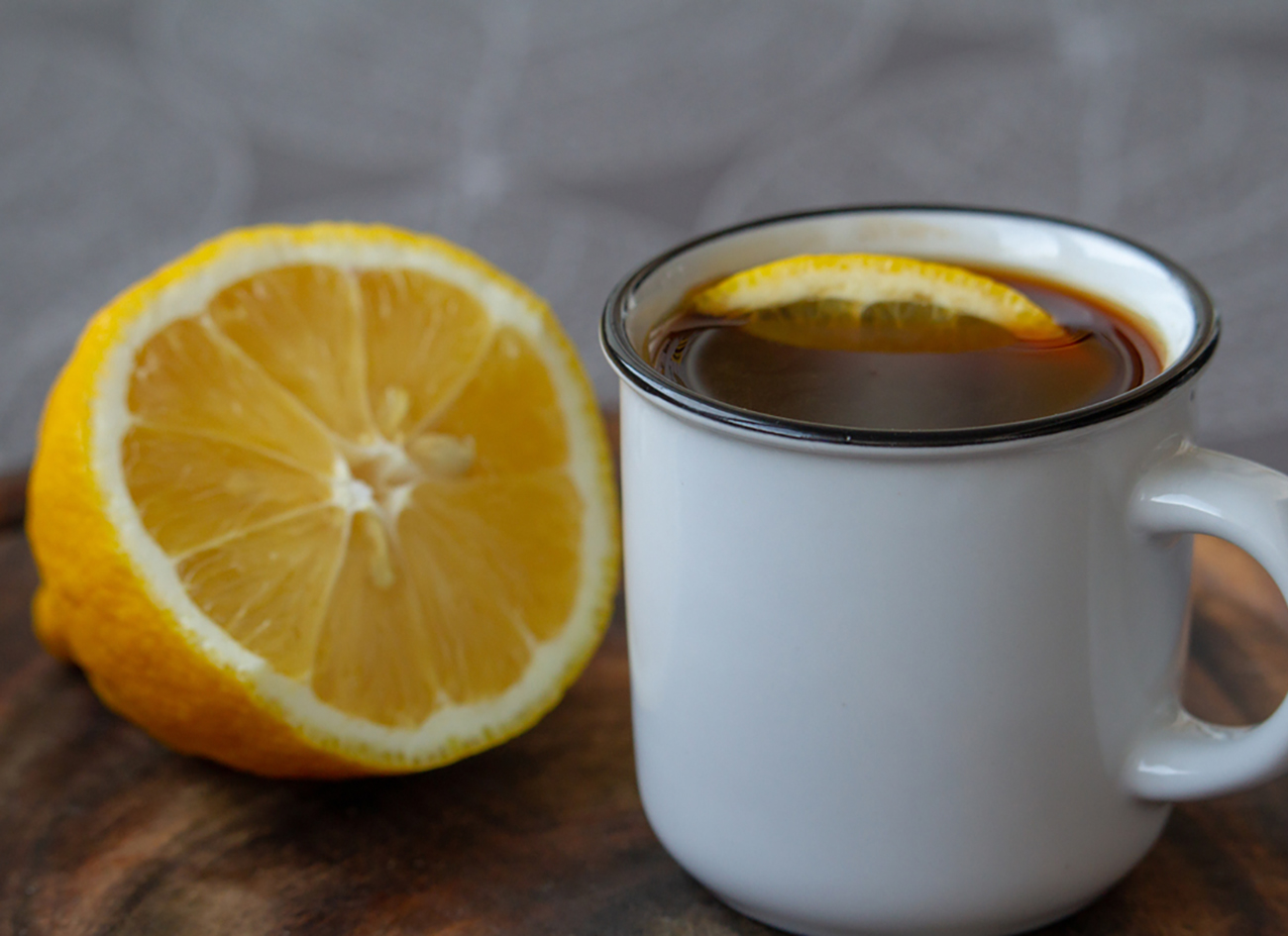 Cup of black coffee with a slice of lemon on a grey tablecloth, selective focus