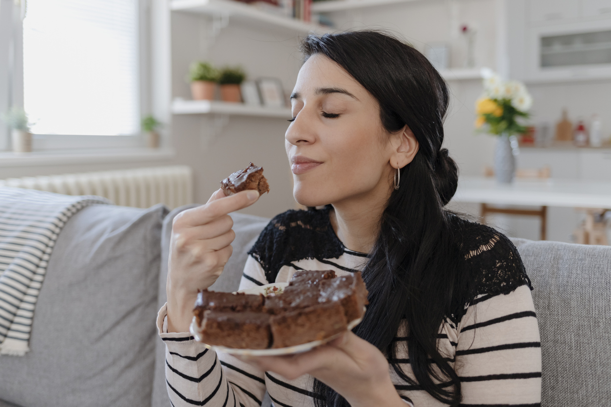 Young Woman Eating Unhealthy Food. Sweetness Indulging and Fattening Concept. Girl Biting Chocolate Cake, High-calorie Sweet Food, Increased Glucose Diabetes. Sweet food addiction.