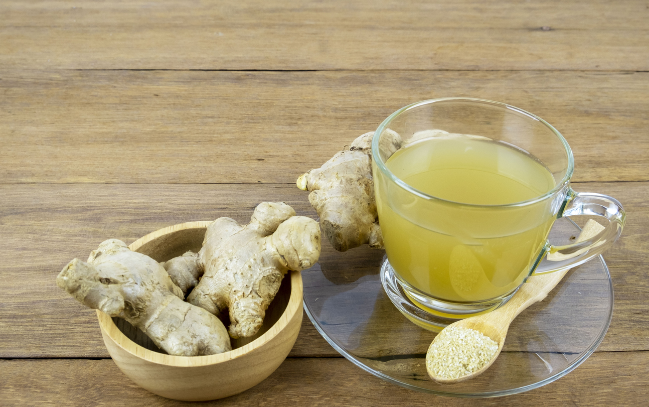 Ginger and ginger tea in a cup on a wooden table at home.