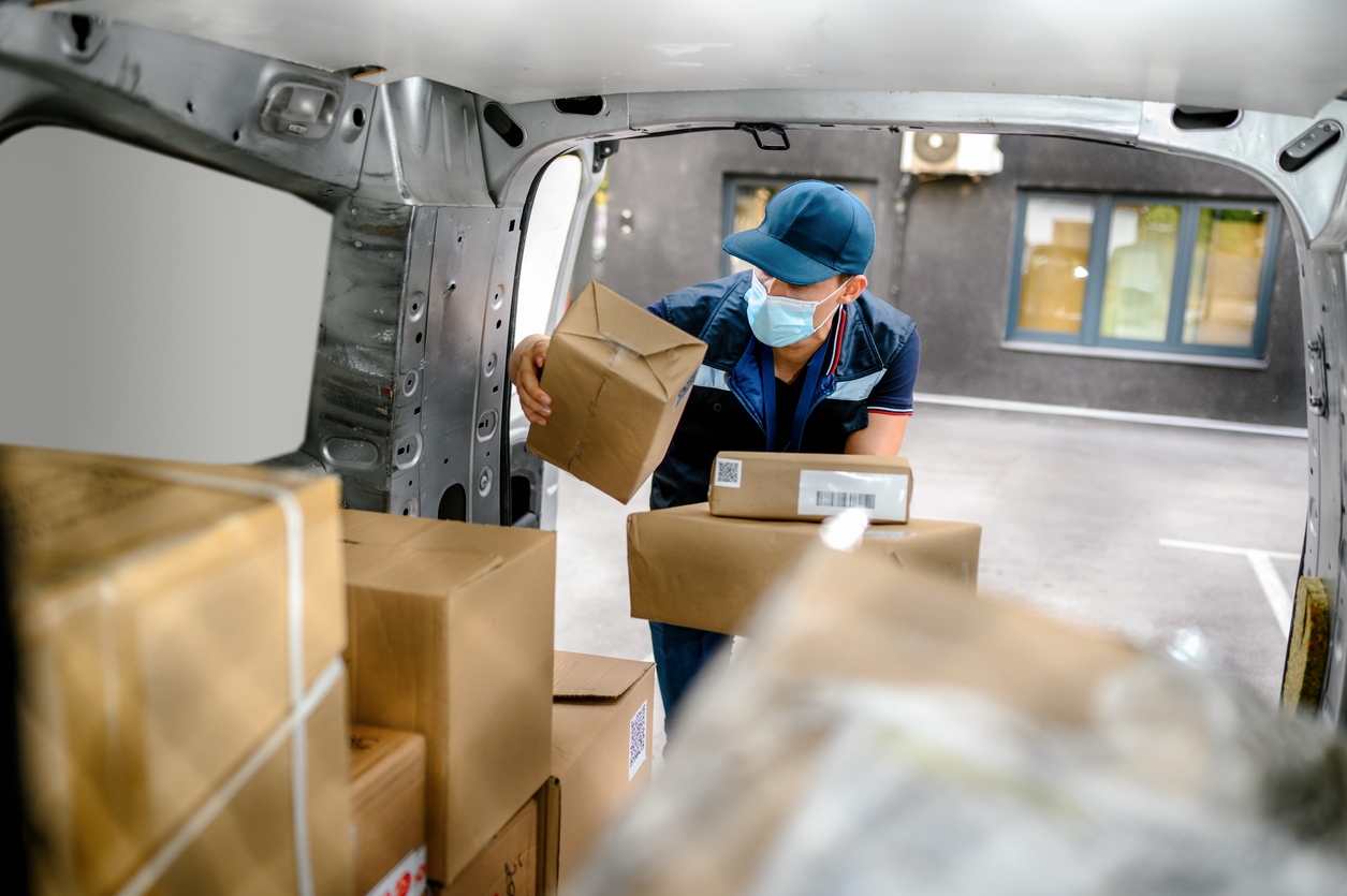 Delivery man holding cardboard box and unloading parcel for delivery.
