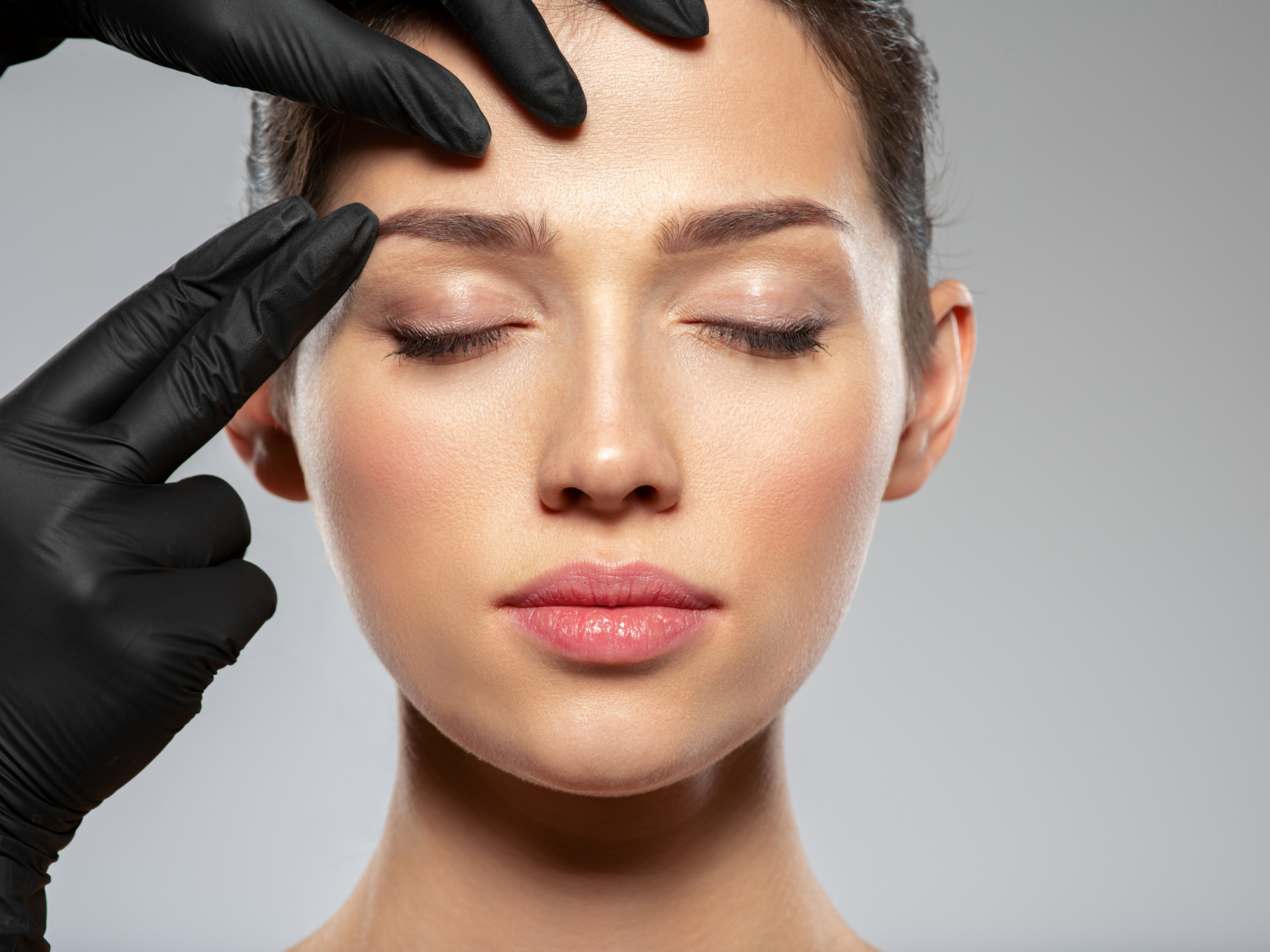 Face skin check before plastic surgery. Beautician touching woman face. Doctor checks a skin before plastic surgery. Beauty treatments. Plastic surgery doctor is touching face of a patient by hands