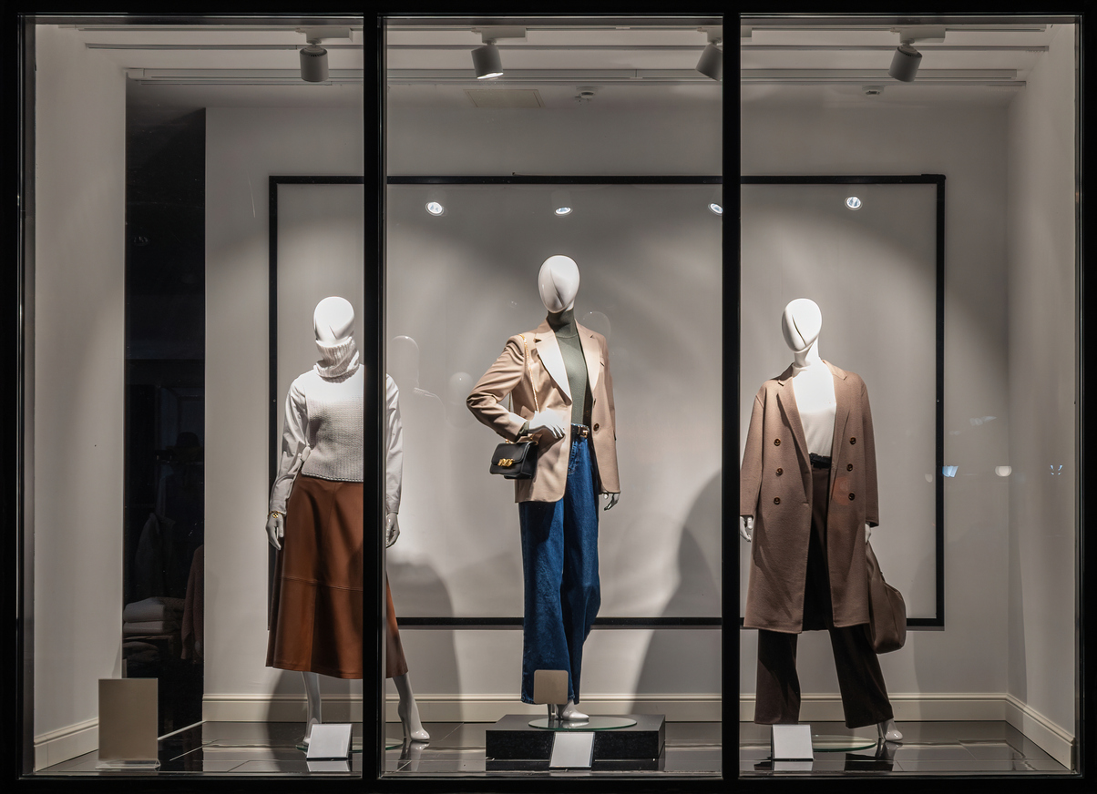 Shop windows and mannequins. Fashion Store exterior. City Night Boutique. Front View from street outdoor. LED light. City facade background