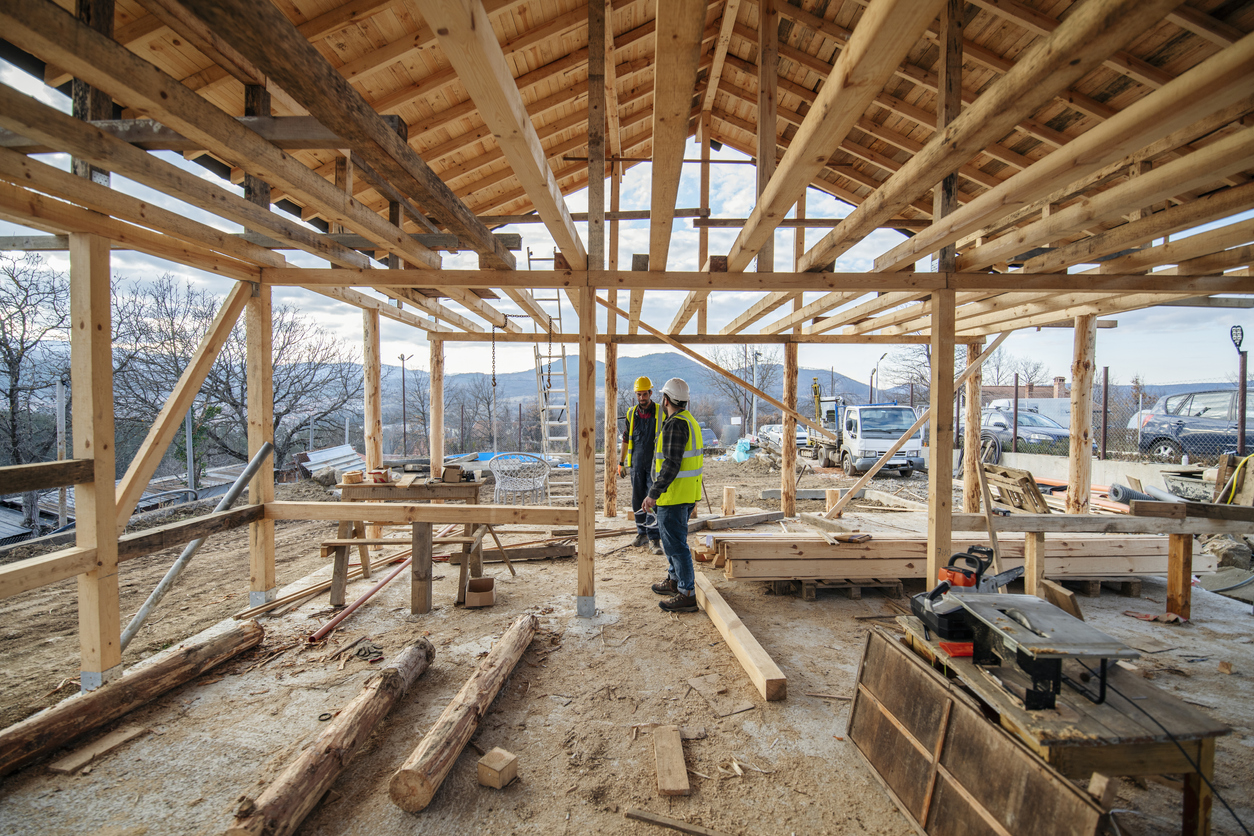Construction workers in building site of wooden house.