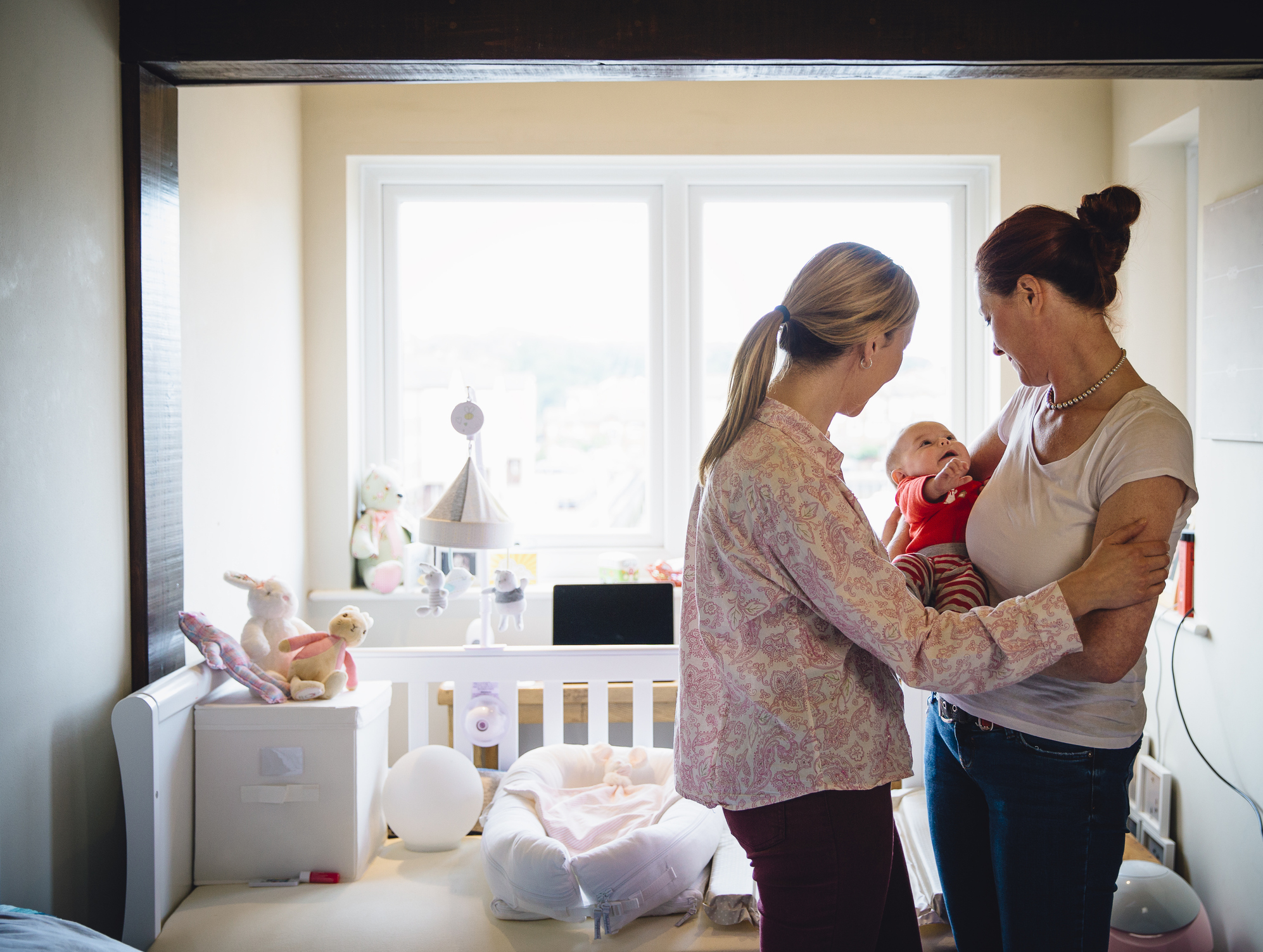 Same sex couple cuddling with their baby daughter in their bedroom.