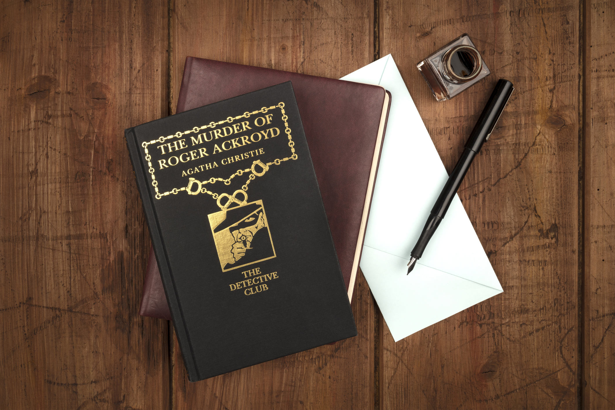 Madrid, Spain, March, 5, 2018. The Murder of Roger Ackroyd, a detective novel by Agatha Christie, with a leather journal, a blue envelope, and an ink well and pen, on a dark background with copy space