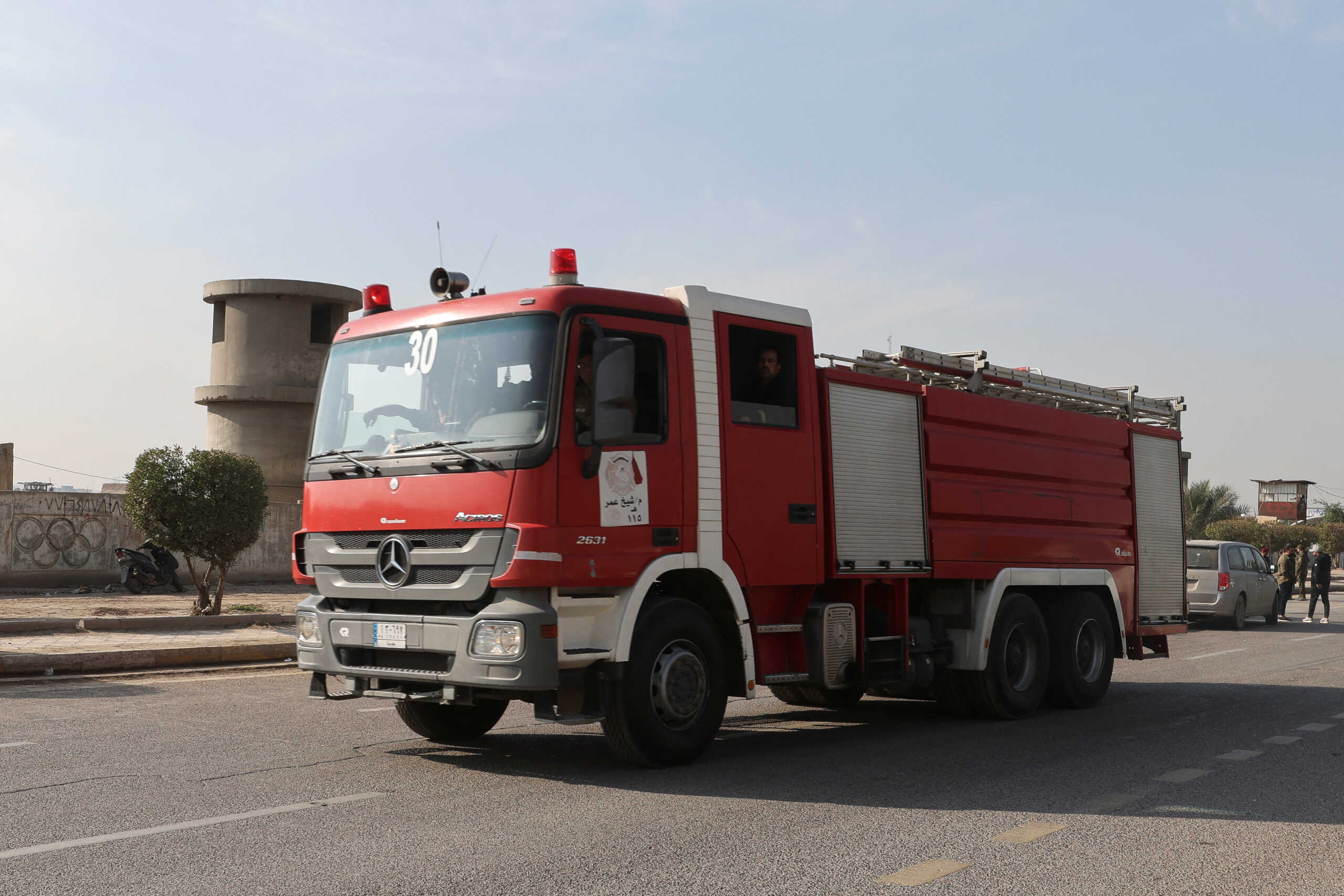 Iraqi firefighters sit in a fire truck at a street after an attack by a drone strike on an Iran-backed militia headquarters in Baghdad, Iraq January 4, 2024. REUTERS