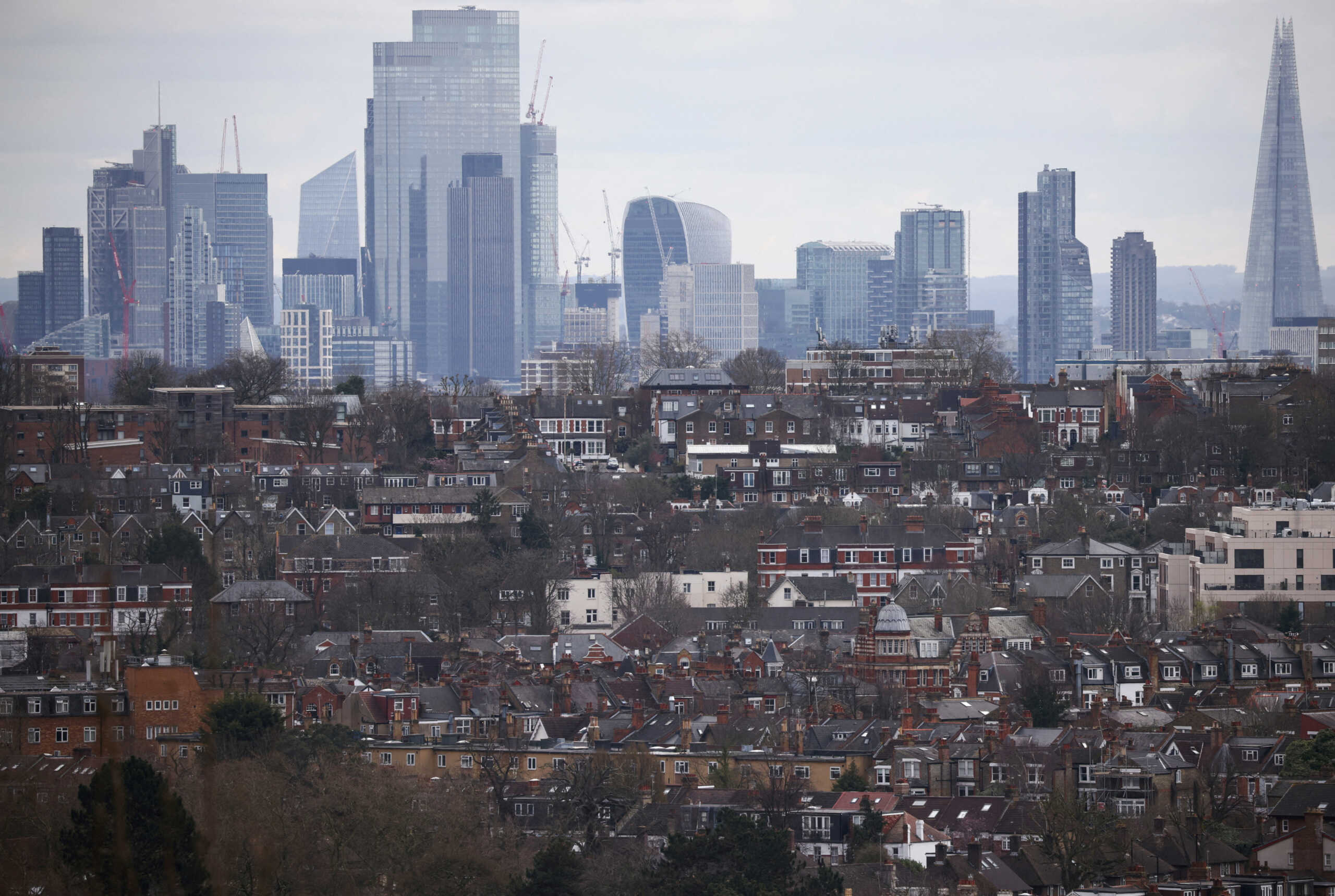 FILE PHOTO: Rows of houses lie in front of the City of London skyline in London, Britain, March 19, 2023. REUTERS