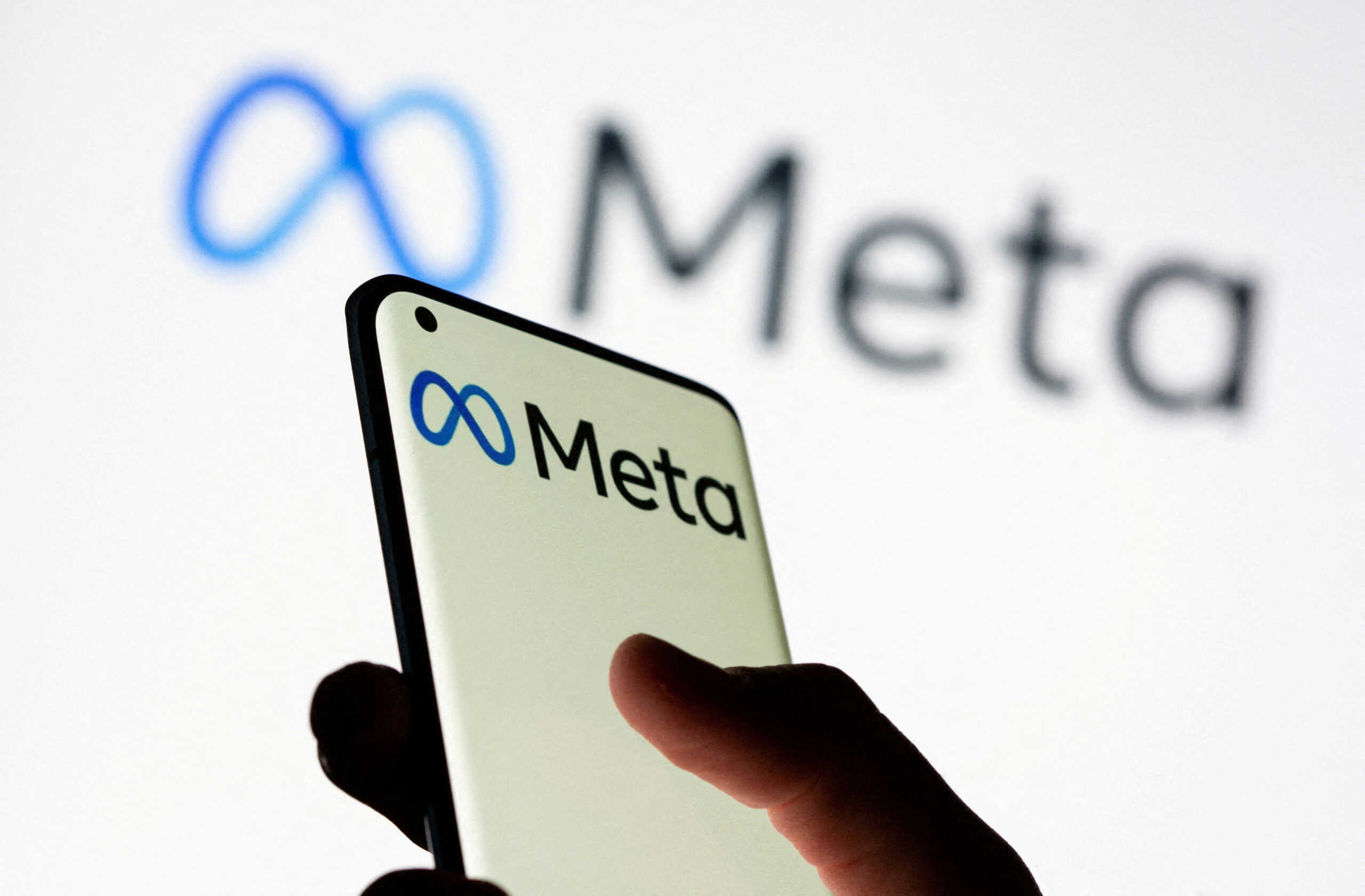 FILE PHOTO: Woman holds smartphone with Meta logo in front of a displayed Facebook's new rebrand logo Meta in this illustration picture taken October 28, 2021. REUTERS