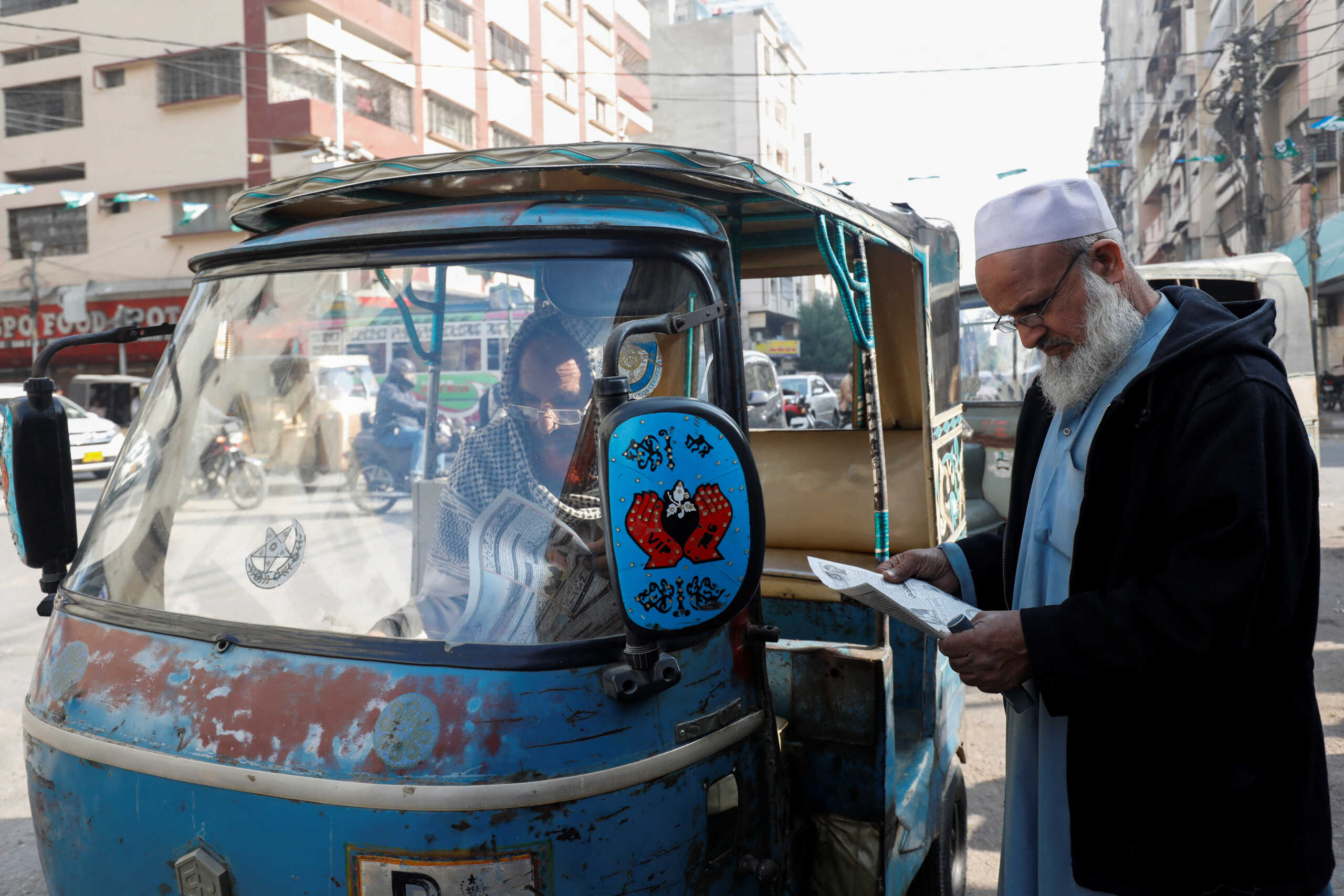 Men read newspapers, after the Pakistani foreign ministry said the country conducted strikes targeting separatist militants inside Iran, along a road in Karachi, Pakistan January 18, 2024. REUTERS