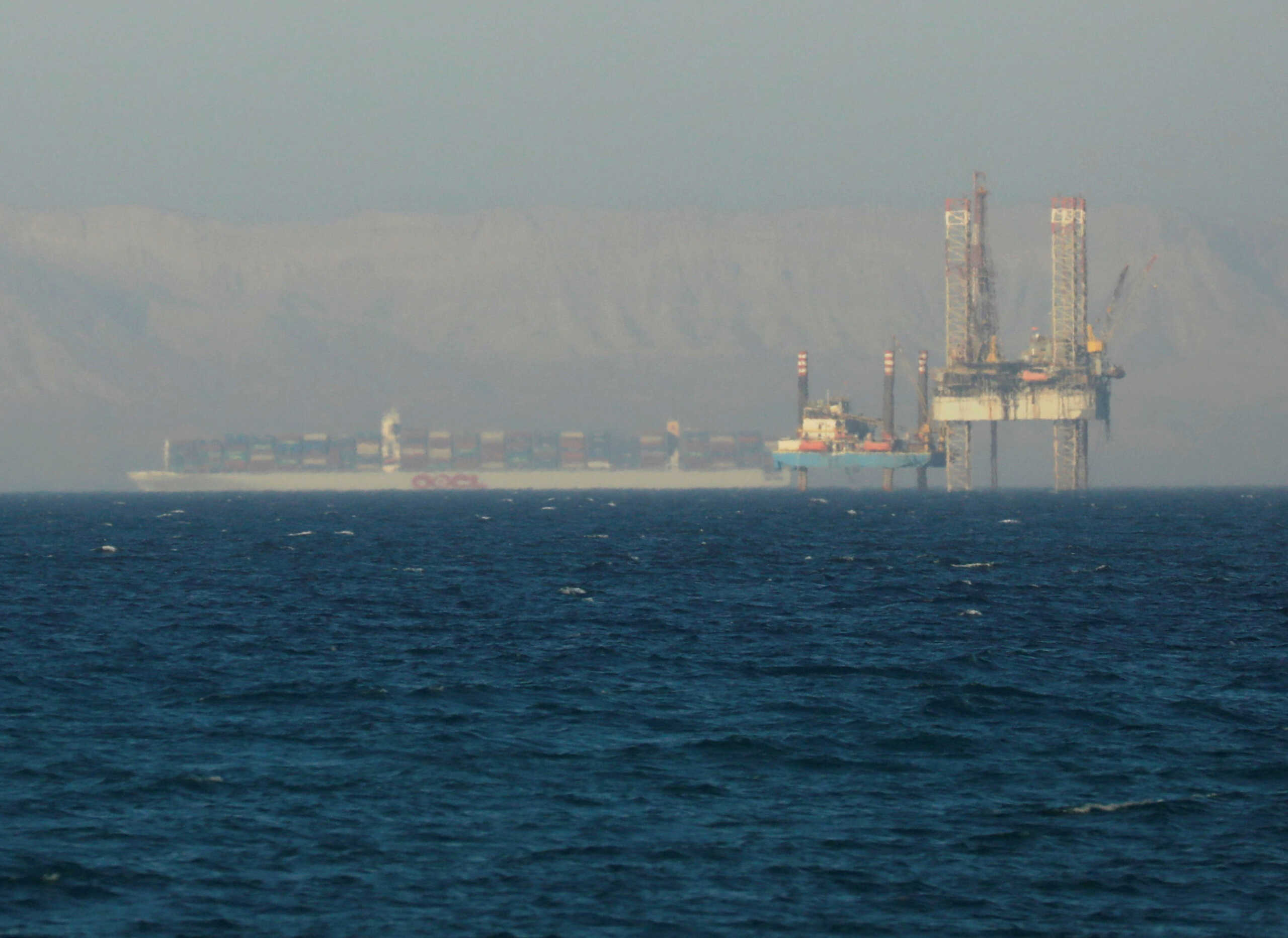 FILE PHOTO: A container ship crosses an oil platform at the Gulf of Suez towards the Red Sea before entering the Suez Canal, outside of Cairo, Egypt September 1, 2020. Picture taken September 1, 2020. REUTERS