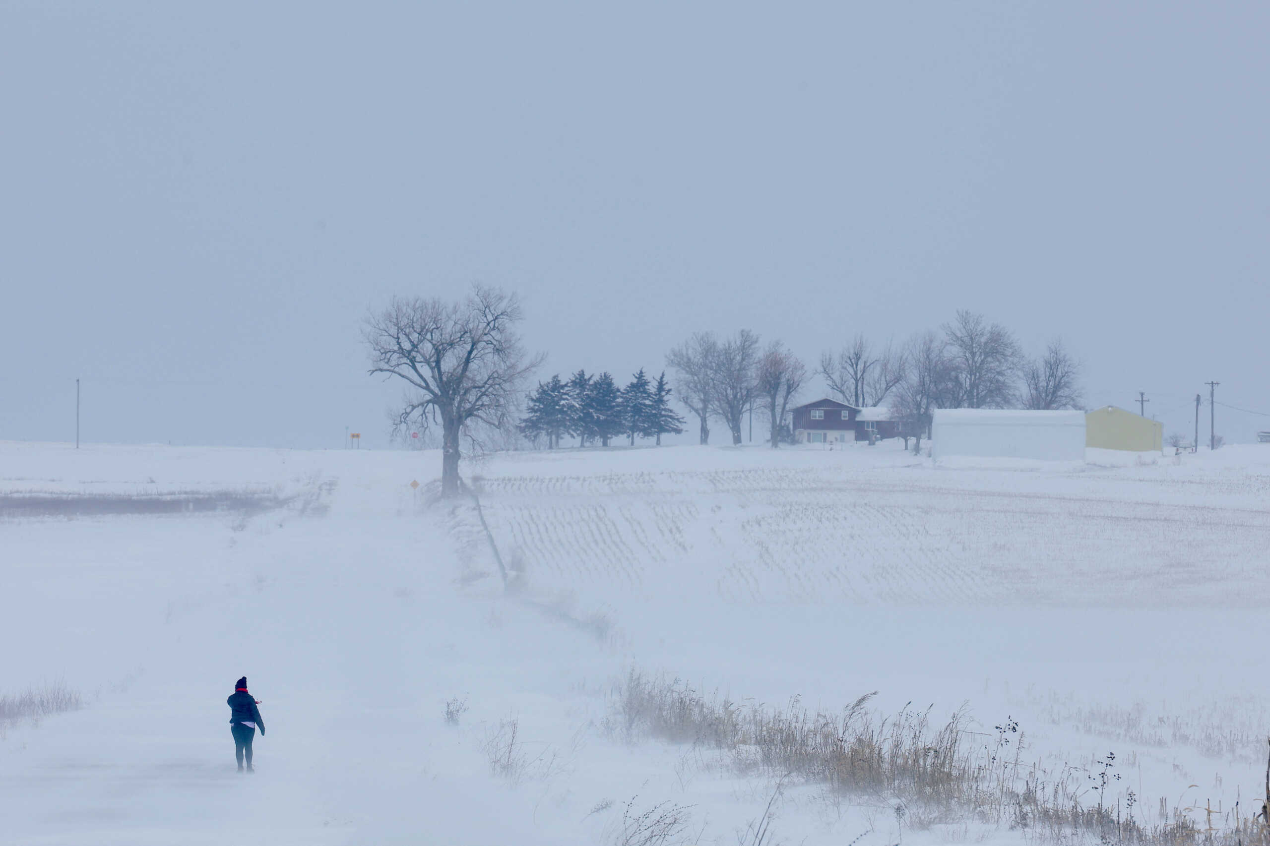 A person walks through the blowing snow and cold that has hit the state ahead of the U.S. presidential caucus elections, in Chelsea, Iowa, U.S., January 13, 2024.   REUTERS