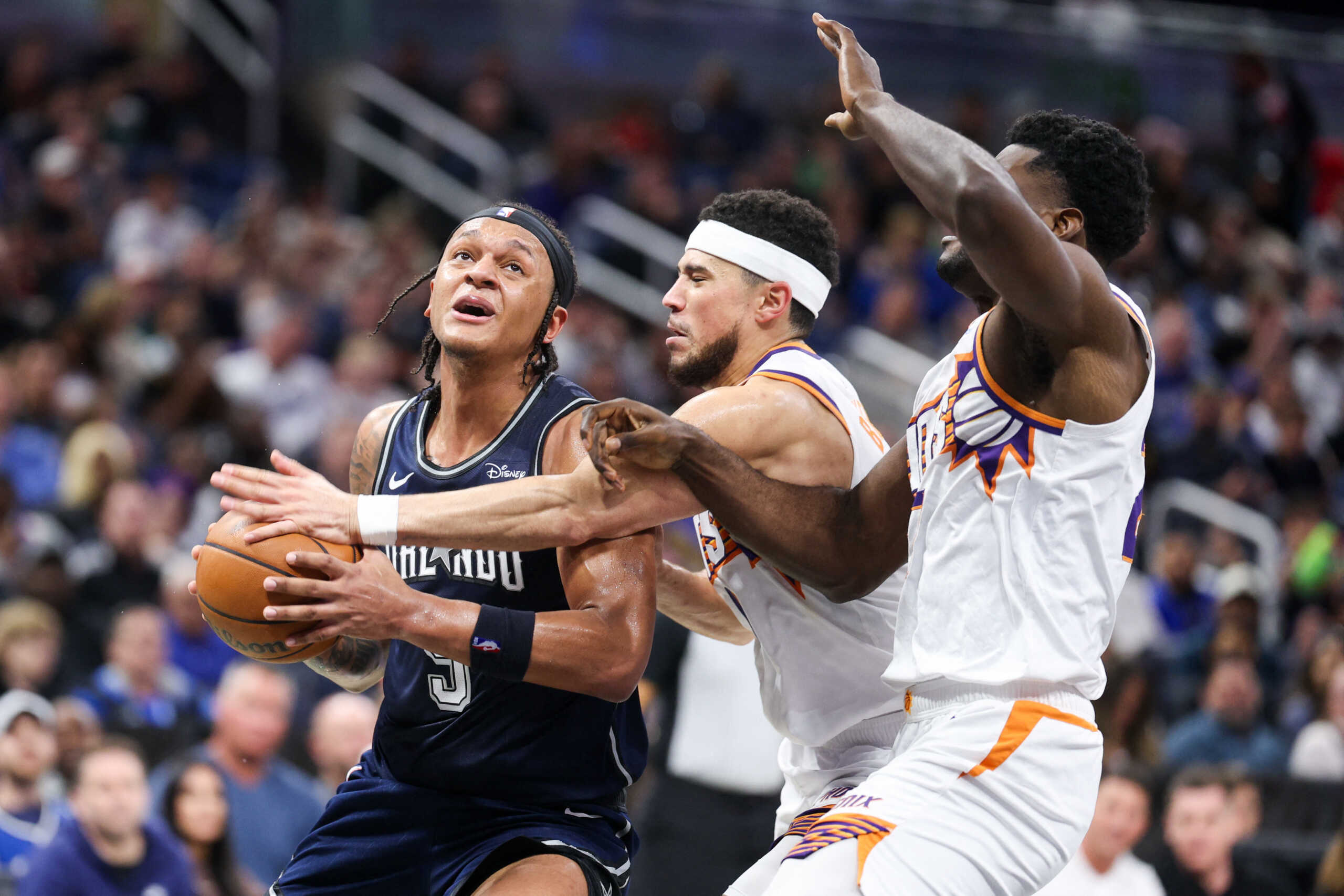 Jan 28, 2024; Orlando, Florida, USA;  Orlando Magic forward Paolo Banchero (5) is fouled by Phoenix Suns guard Devin Booker (1) in the third quarter at the Kia Center. Mandatory Credit: Nathan Ray Seebeck-USA TODAY Sports