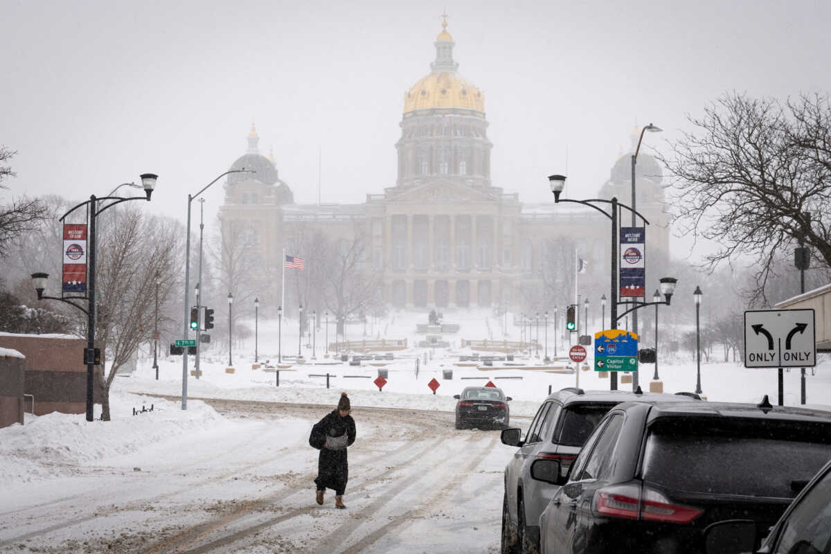 A woman walks in the street in front of Iowa state capitol after a blizzard left several inches of snow, in downtown Des Moines, Iowa, U.S., January 13, 2024. REUTERS