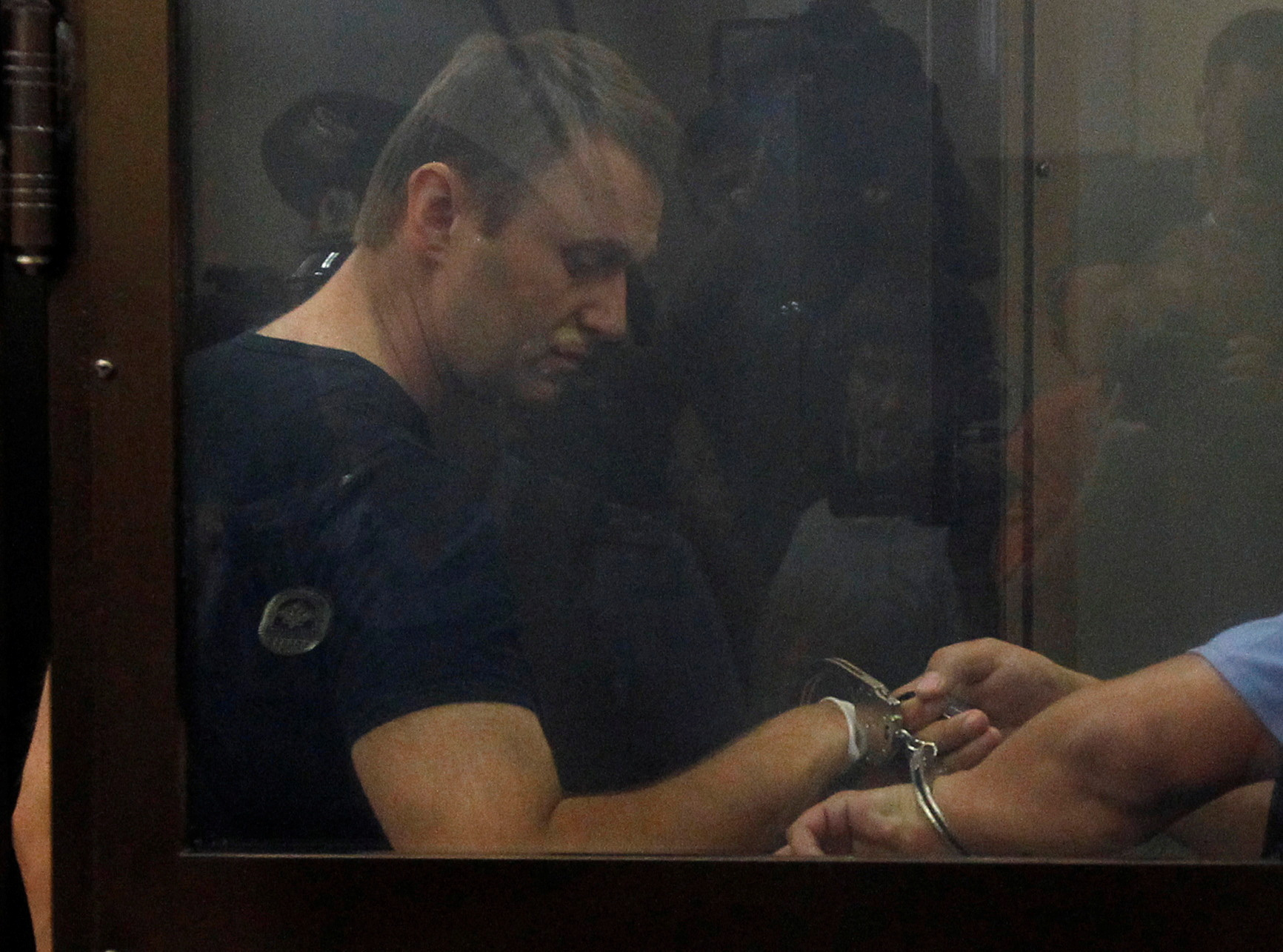 FILE PHOTO: An Interior Ministry officer removes handcuffs from Russian protest leader Alexei Navalny during a court session in Kirov, Russia, July 19, 2013. REUTERS