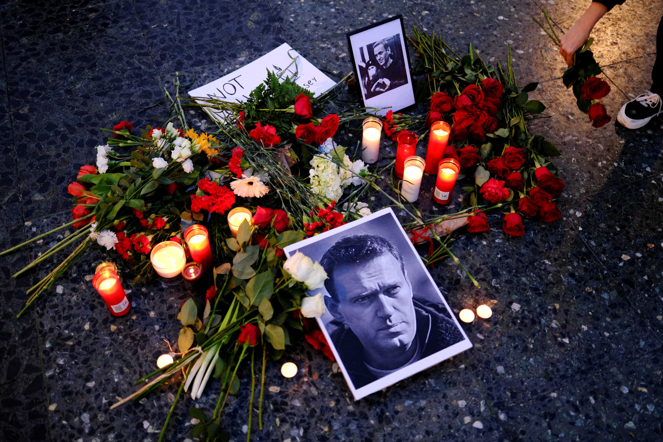 A woman places a flower next to pictures of Russian opposition leader Alexei Navalny, during a protest, following his death, at the Catalunya square, Barcelona, Spain, February 16, 2024. REUTERS