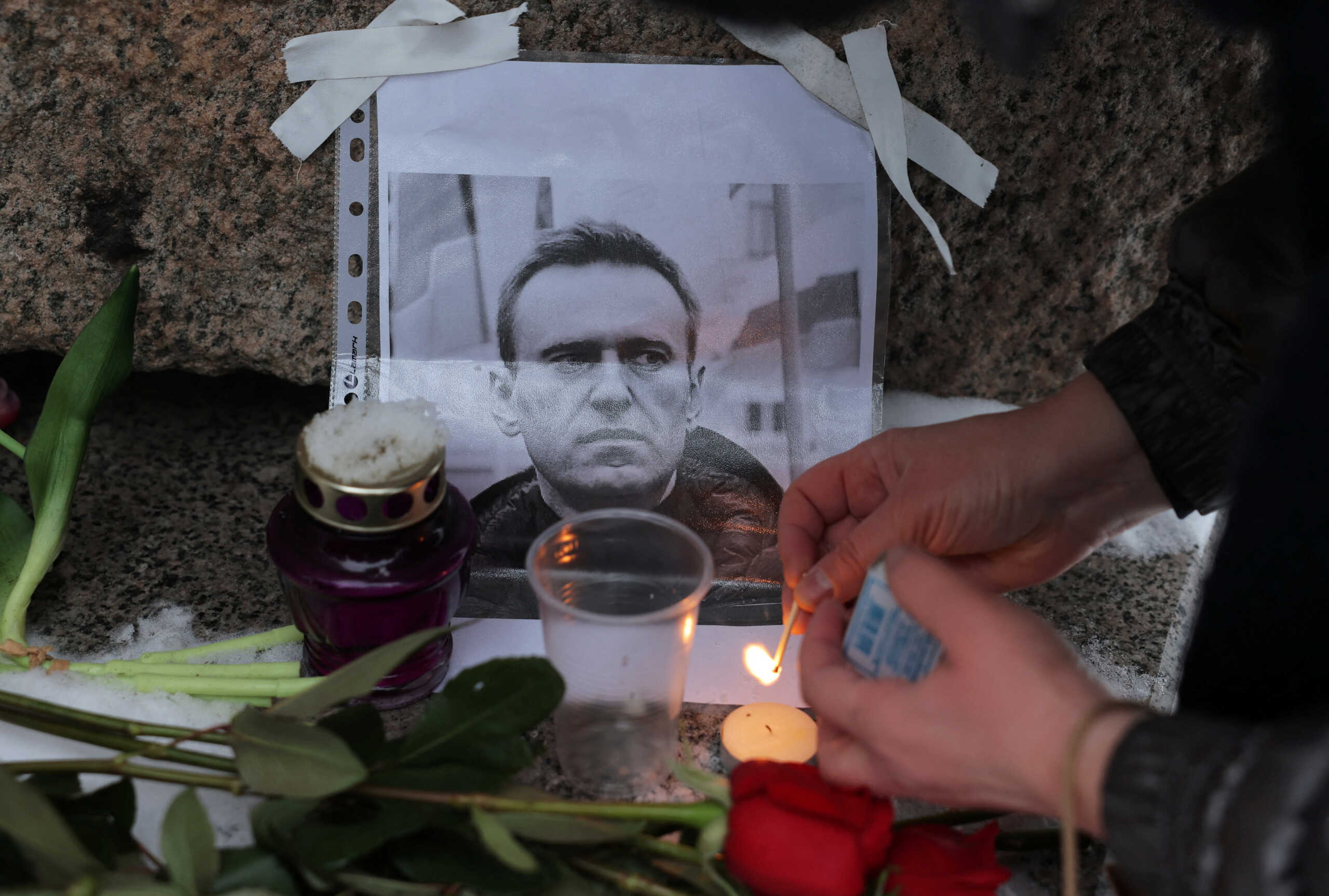A person lights a candle next to a portrait of Russian opposition leader Alexei Navalny at the monument to the victims of political repressions following Navalny's death, in Saint Petersburg, Russia February 16, 2024. REUTERS