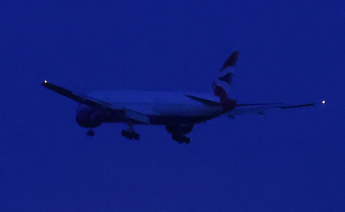 A British Airways passenger plane makes its landing approach to Heathrow Airport, with the moon seen behind, before dawn, in London, Britain, February 23, 2024. REUTERS