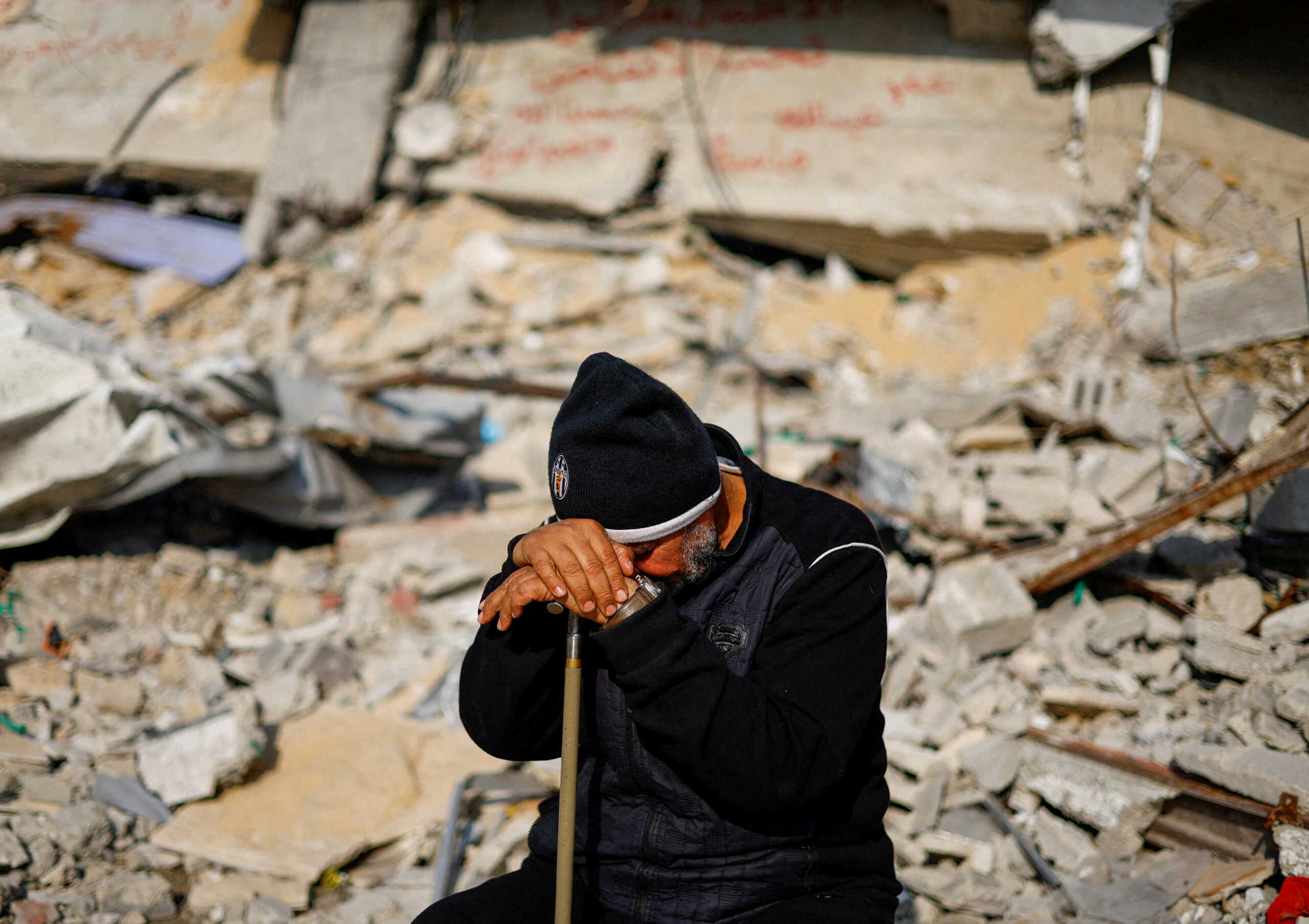 FILE PHOTO: Ziad Mansour, a neighbour of the Abu Aweidah family, sits next to writing painted on a wall amid the rubble of the family's house, which was destroyed in a deadly Israeli strike amid the ongoing conflict between Israel and the Palestinian Islamist group Hamas, in Rafah, Gaza Strip, January 9, 2024. REUTERS