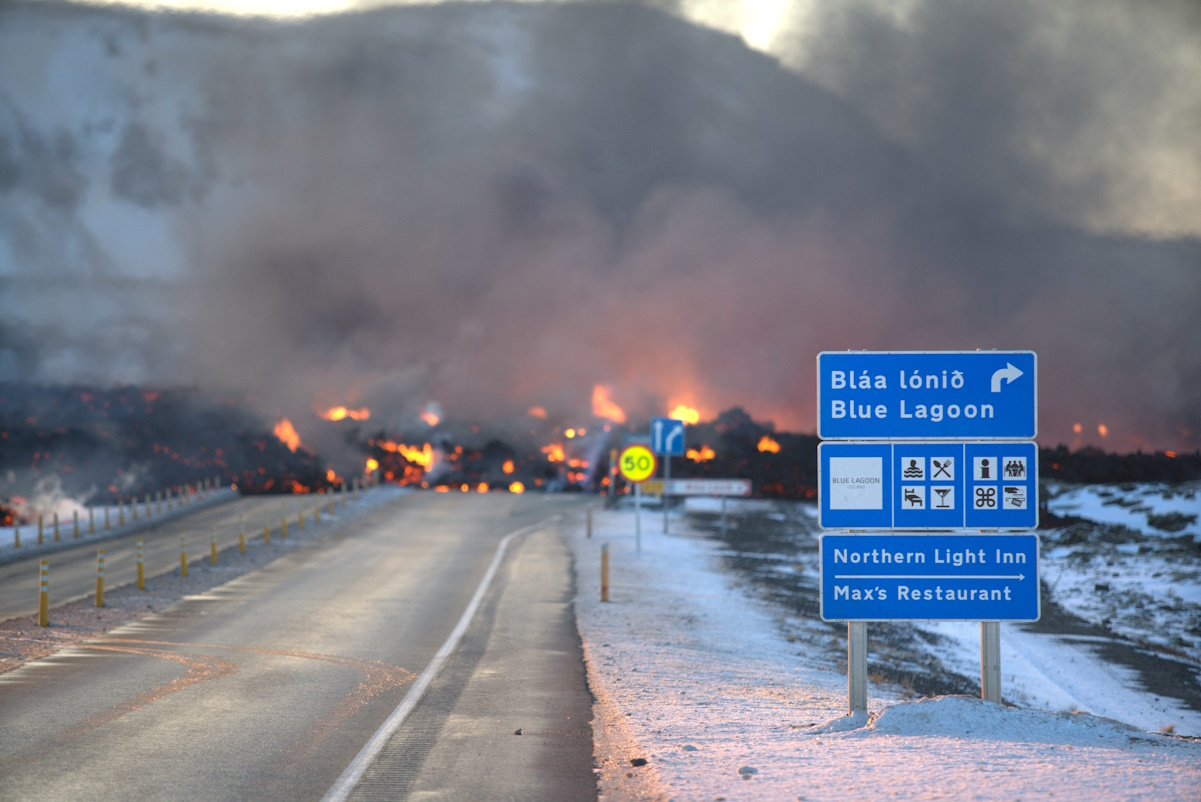 Lava from a volcanic eruption flows across a road north of Grindavik, Iceland, February 8, 2024. REUTERS