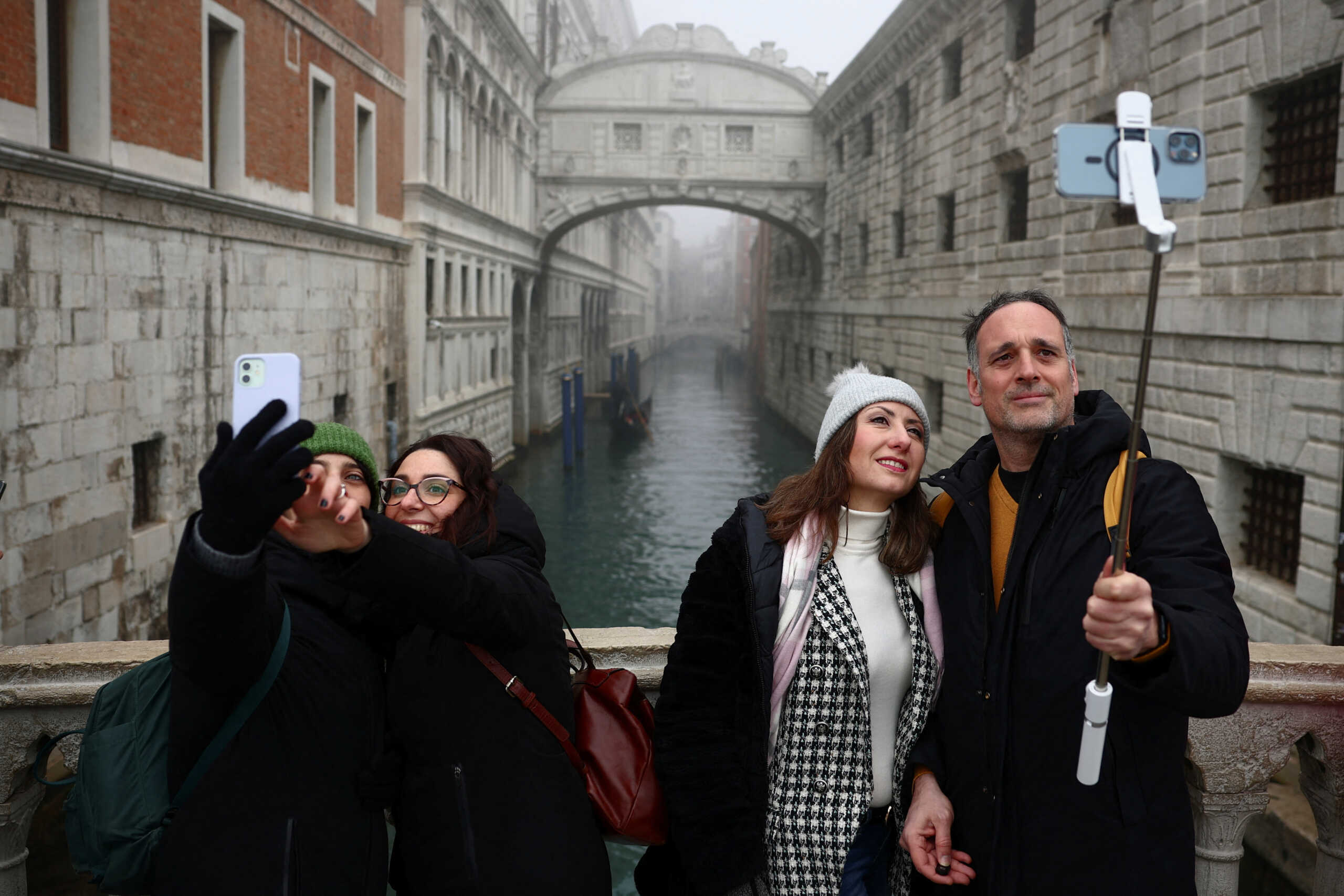 Tourists take selfies near Ponte de Sospiri bridge during Venice carnival in Venice, Italy, January 27, 2024. REUTERS