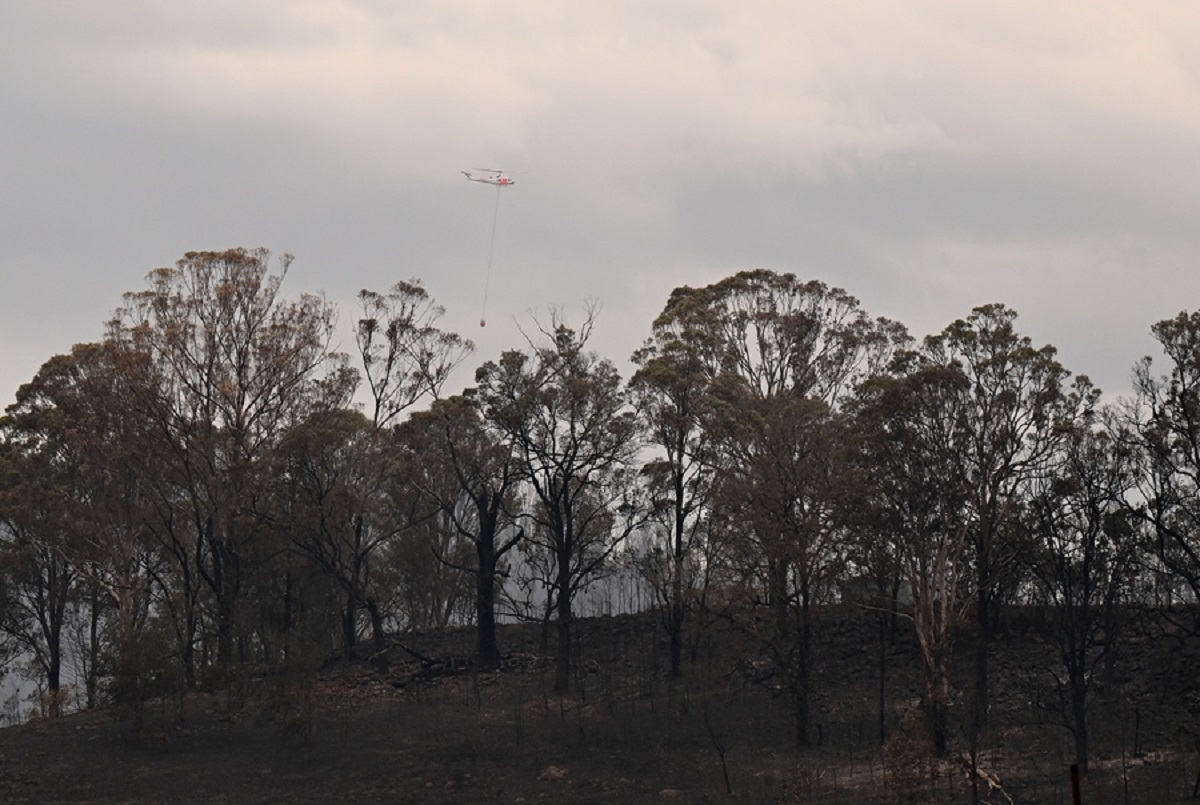 epa10898720 A helicopter drops water over the fireground near Coolagolite, NSW, Australia, 04 October 2023. Homes have been lost on the NSW south coast after firefighters battled a large blaze overnight.  EPA