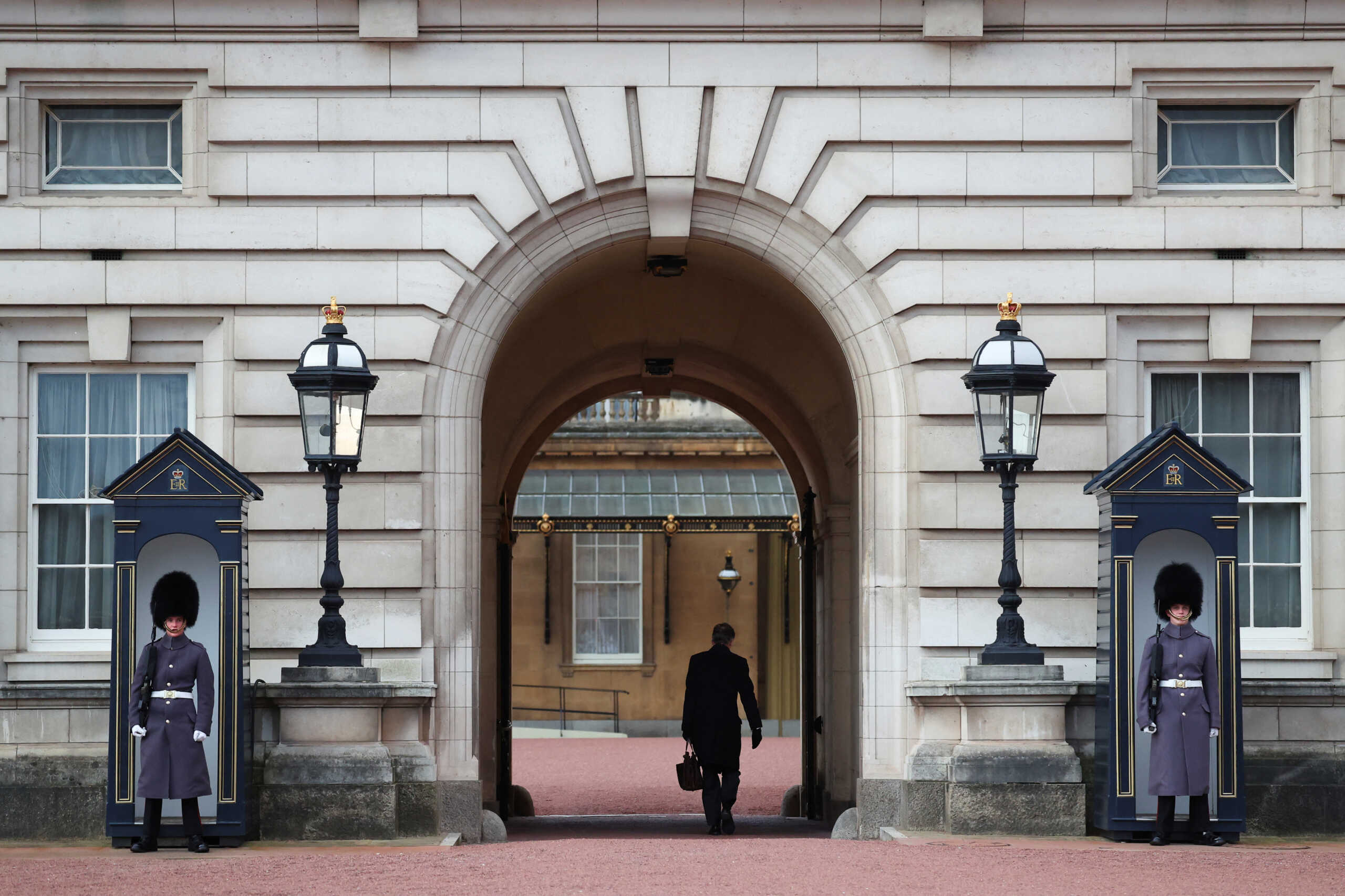 An employee walks at Buckingham Palace as guards stand outside, after it was announced that Britain's King Charles has been diagnosed with cancer, in London, Britain, February 6, 2024. REUTERS