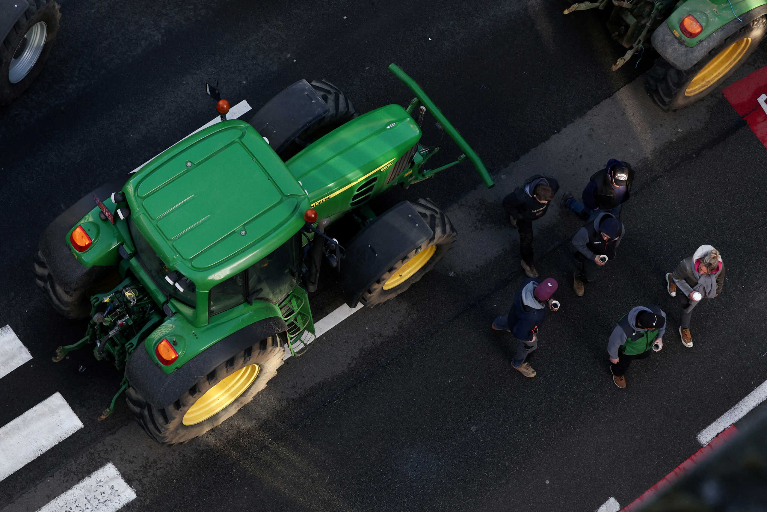 People walk next to a tractor as farmers from Belgium and other European countries block a road near the European Parliament during a protest over price pressures, taxes and green regulation, on the day of an EU summit in Brussels, Belgium February 1, 2024. REUTERS