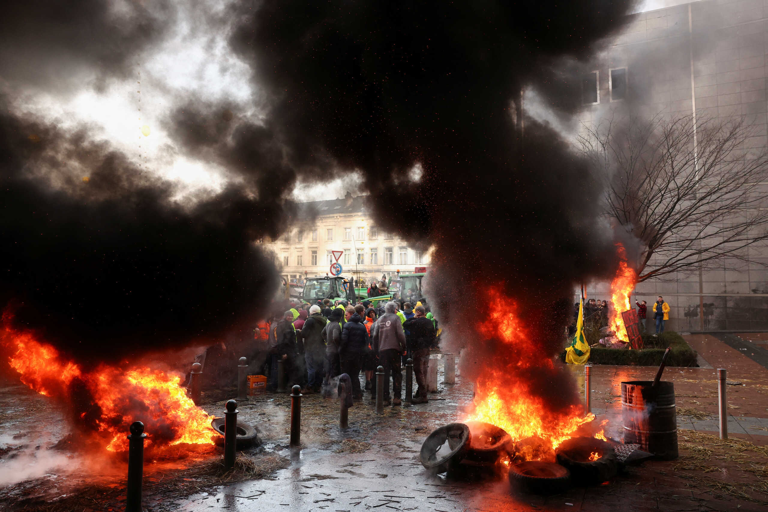 Smoke rises from objects set on fire as people gather in front of the European Union headquarters as Belgian farmers use their tractors to block the headquarters, as they protest over price pressures, taxes and green regulation, grievances shared by farmers across Europe, in Brussels, Belgium February 1, 2024. REUTERS
