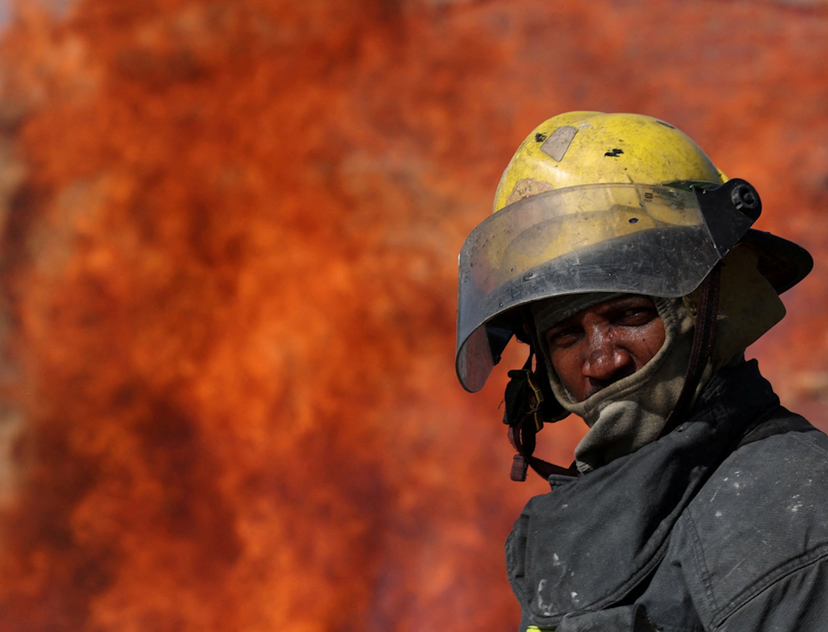 A firefighter views a fire near Observatory, as firefighters remain on high alert amid dry, hot, and windy weather in Cape Town, South Africa, January 25, 2024. REUTERS