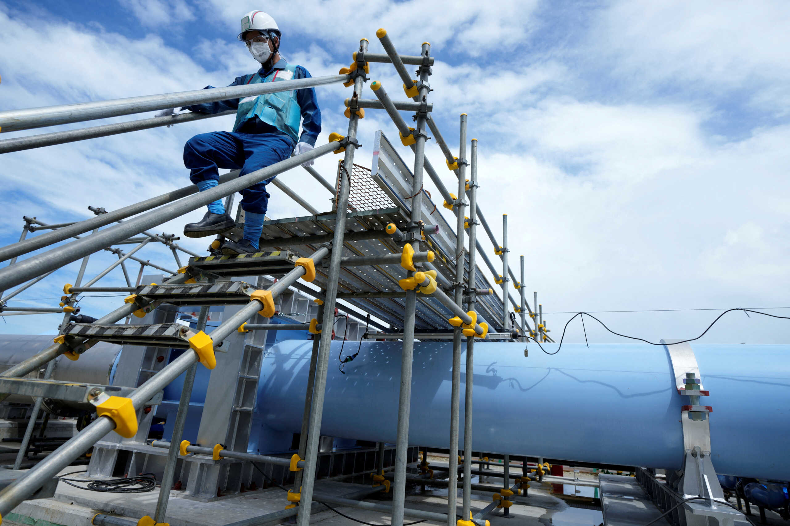 FILE PHOTO: A member of staff walks near a blue pipeline to transport seawater, part of the facility for releasing treated radioactive water to sea from the Fukushima Daiichi nuclear power plant, operated by Tokyo Electric Power Company Holdings, also known as TEPCO, during a treated water dilution and discharge facility tour for foreign media, in Futaba town, northeastern Japan, Sunday, Aug. 27, 2023.     Eugene Hoshiko