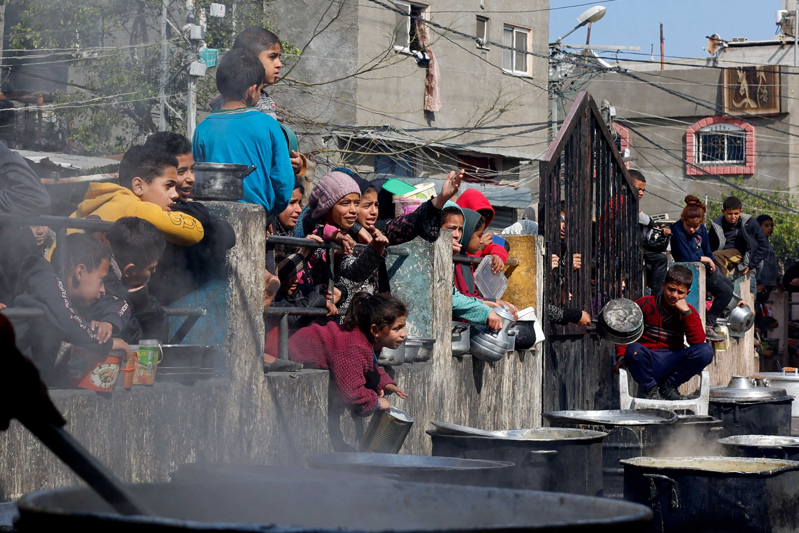 Palestinian children wait to receive food cooked by a charity kitchen amid shortages of food supplies, as the ongoing conflict between Israel and the Palestinian Islamist group Hamas continues, in Rafah, in the southern Gaza Strip, February 20, 2024. REUTERS