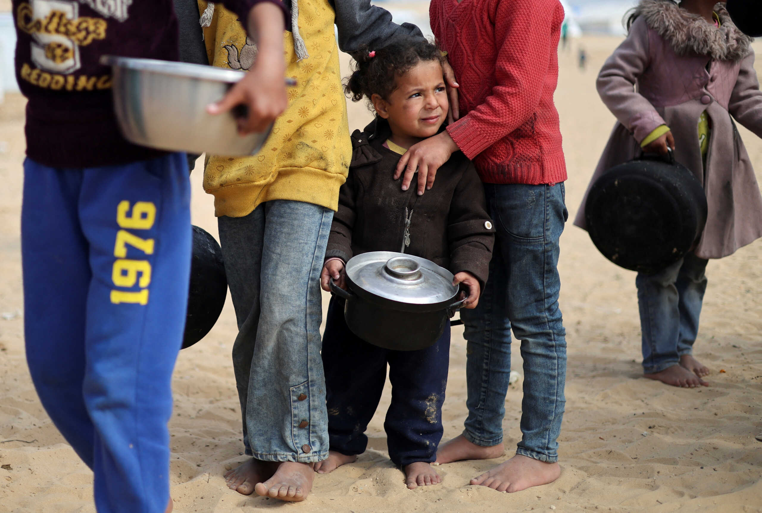 Displaced Palestinian children wait to receive free food at a tent camp, amid food shortages, as the conflict between Israel and Hamas continues, in Rafah in the southern Gaza Strip, February 27, 2024. REUTERS