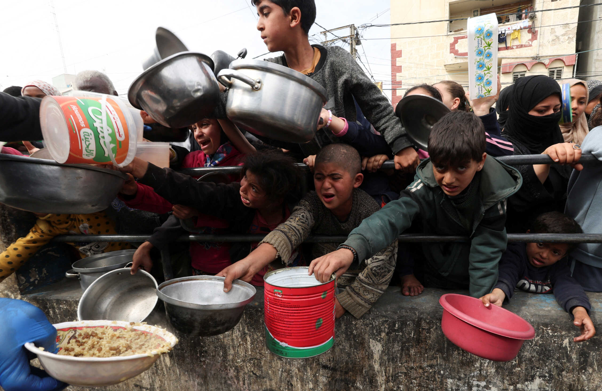Palestinian children wait to receive food cooked by a charity kitchen amid shortages of food supplies, as the ongoing conflict between Israel and the Palestinian Islamist group Hamas continues, in Rafah, in the southern Gaza Strip, February 13, 2024. REUTERS