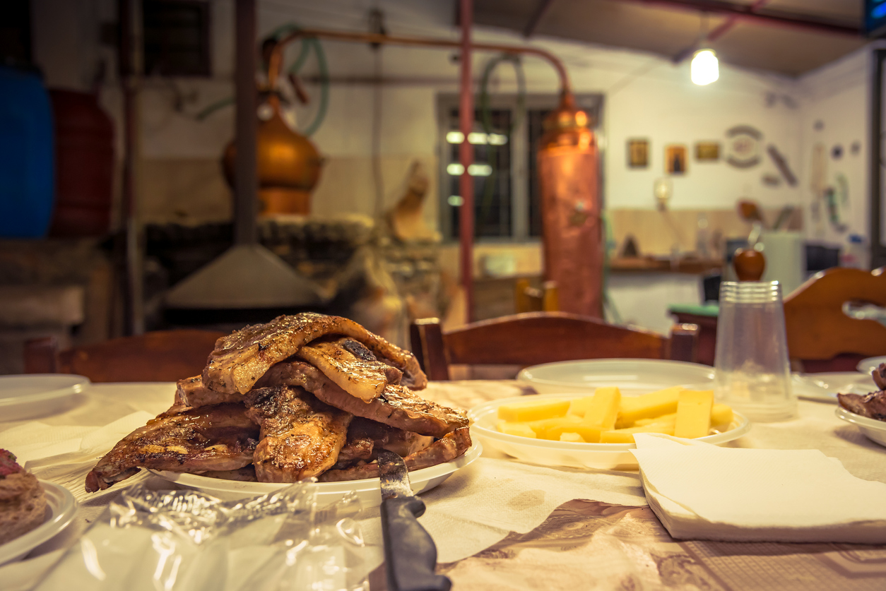 A plate with fresh grilled steaks in Kazani, the traditional distillation of raki - tsipouro in Crete, Greece