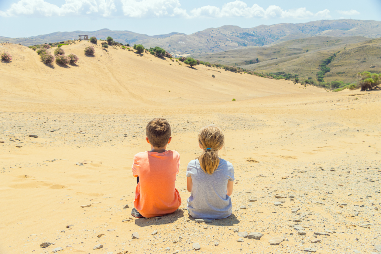 Two children tourists are visiting and looking out over the desert of Lemnos in Greece, the only desert in Europe.