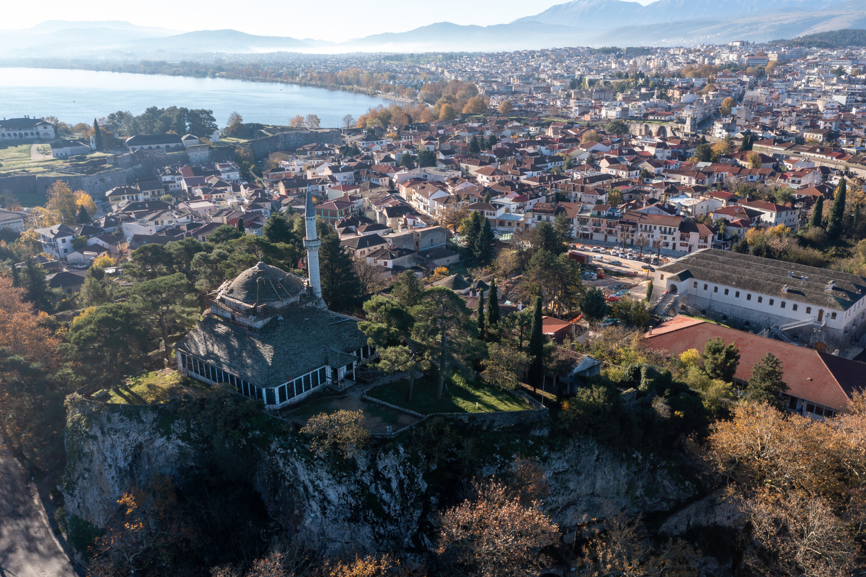 Greece, Ioannina Pamvotida Lake, Epirus. Aerial drone view of Giannena city red tile roof buildings, blue sky background.