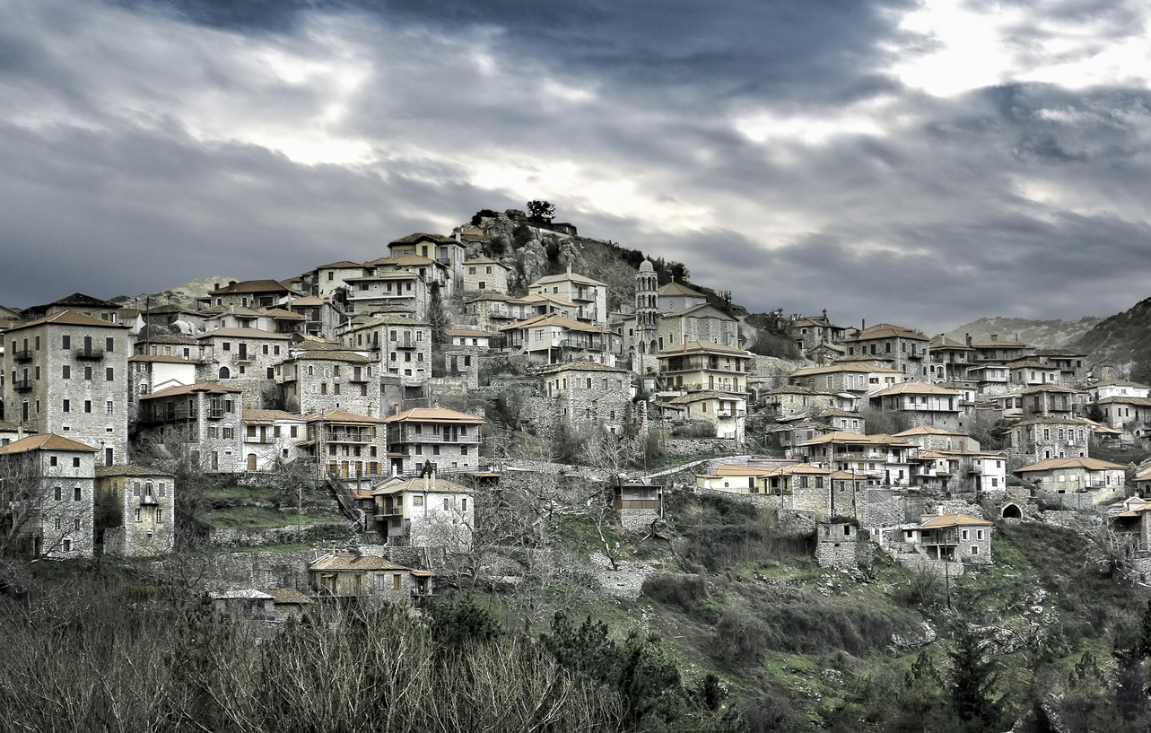view of a stone building on mountain village named Valtesiniko under a heavy cloudy sky. Arcadia- Greece