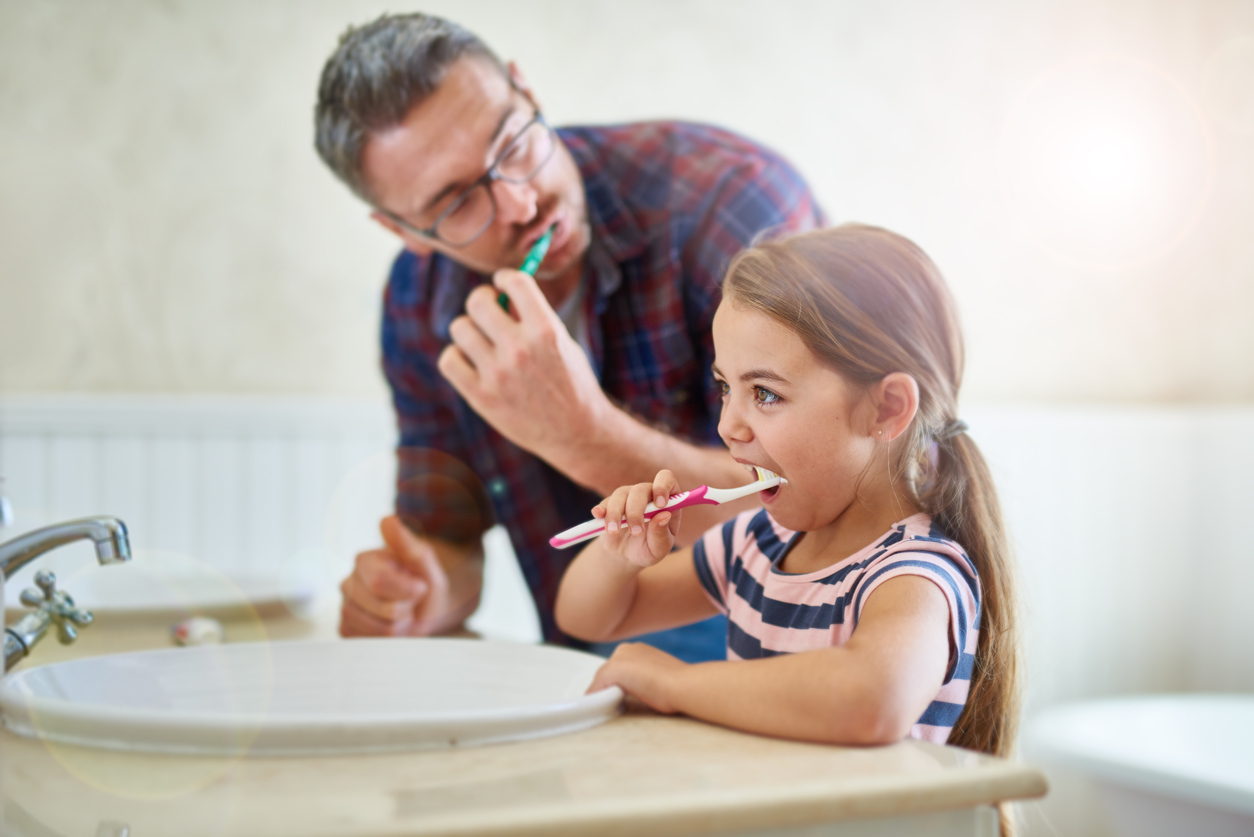 Shot of a father and his daughter brushing their teeth
