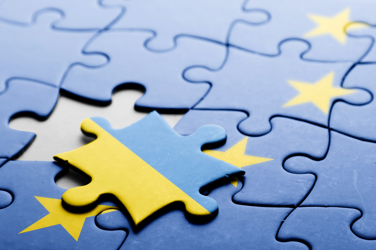 Political relations between Ukraine and European Union, concept puzzle. Flag of European Union on puzzle in background, with one blank place and one piece with flag of Ukraine in front. Studio shot. Horizontal orientation.